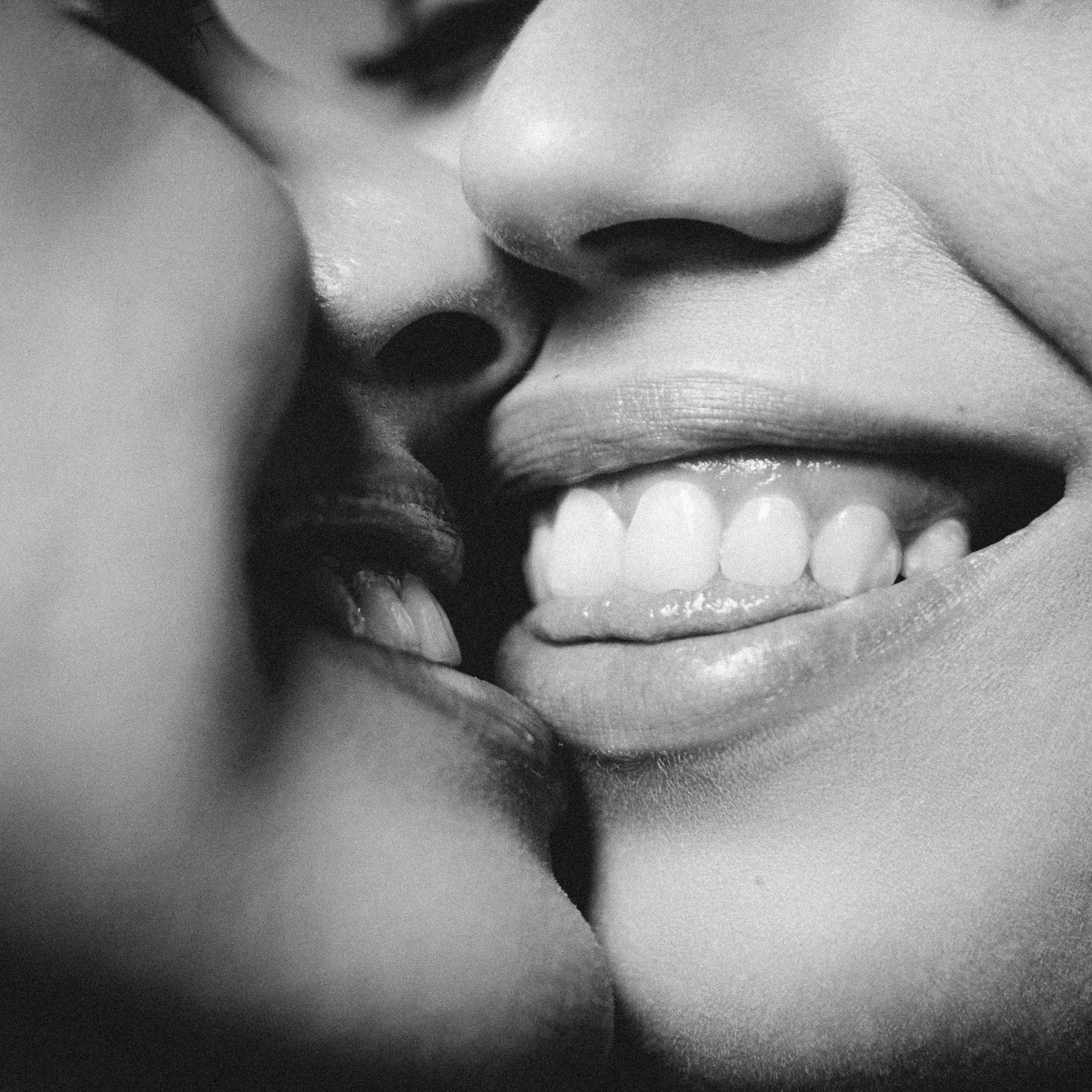 Extreme close-up black and white study of two faces meeting, lips and teeth