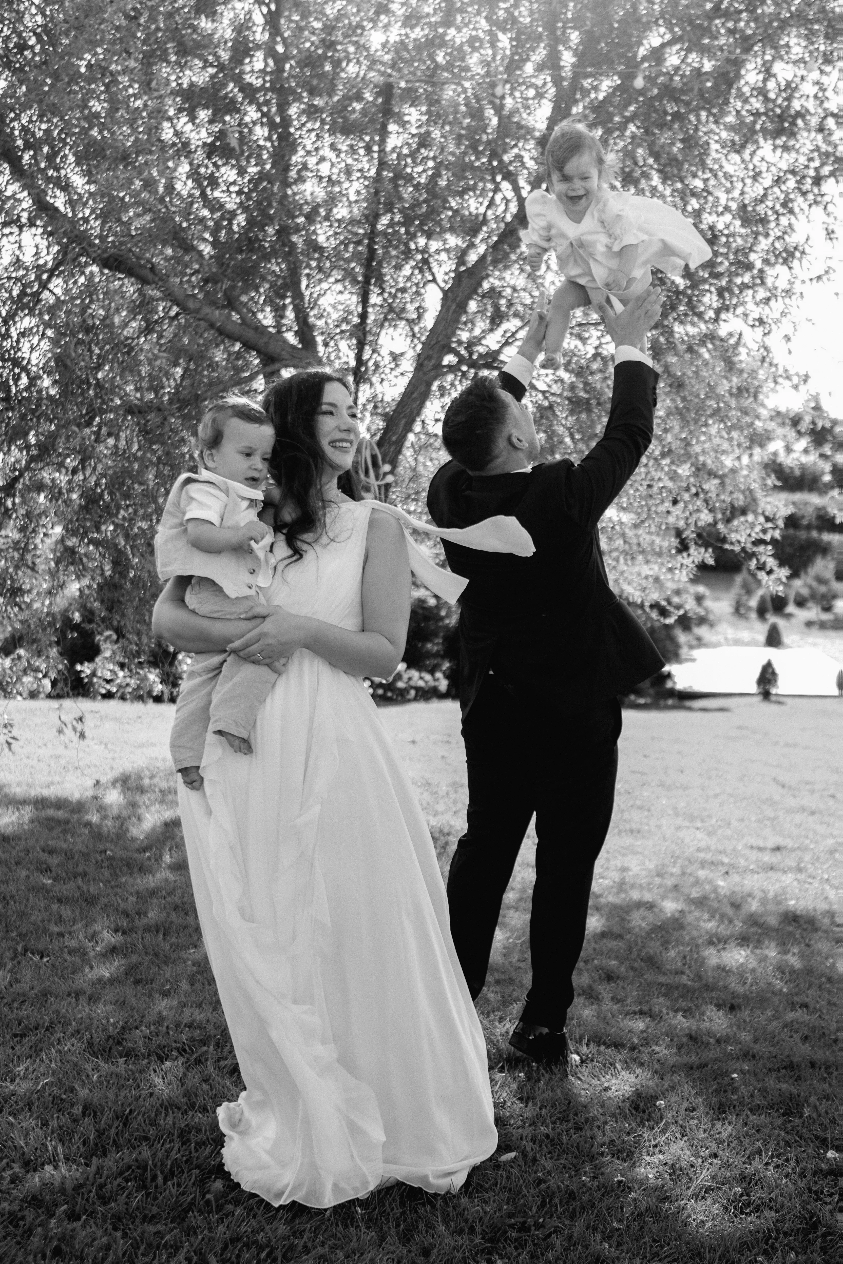 A couple dancing and twirling beneath a tree, black and white