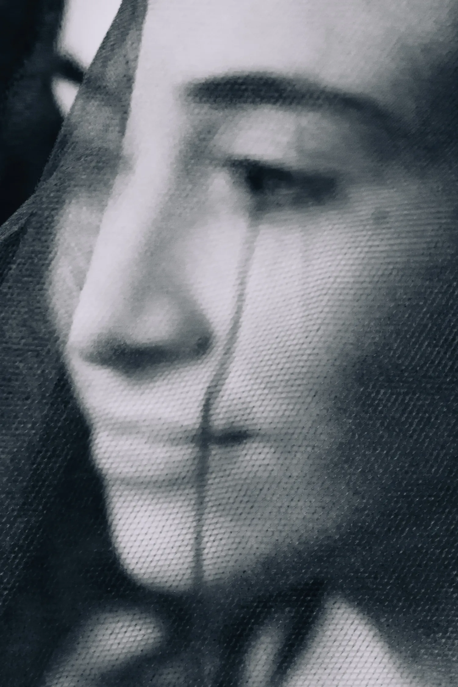 A face dissolved behind sheer fabric