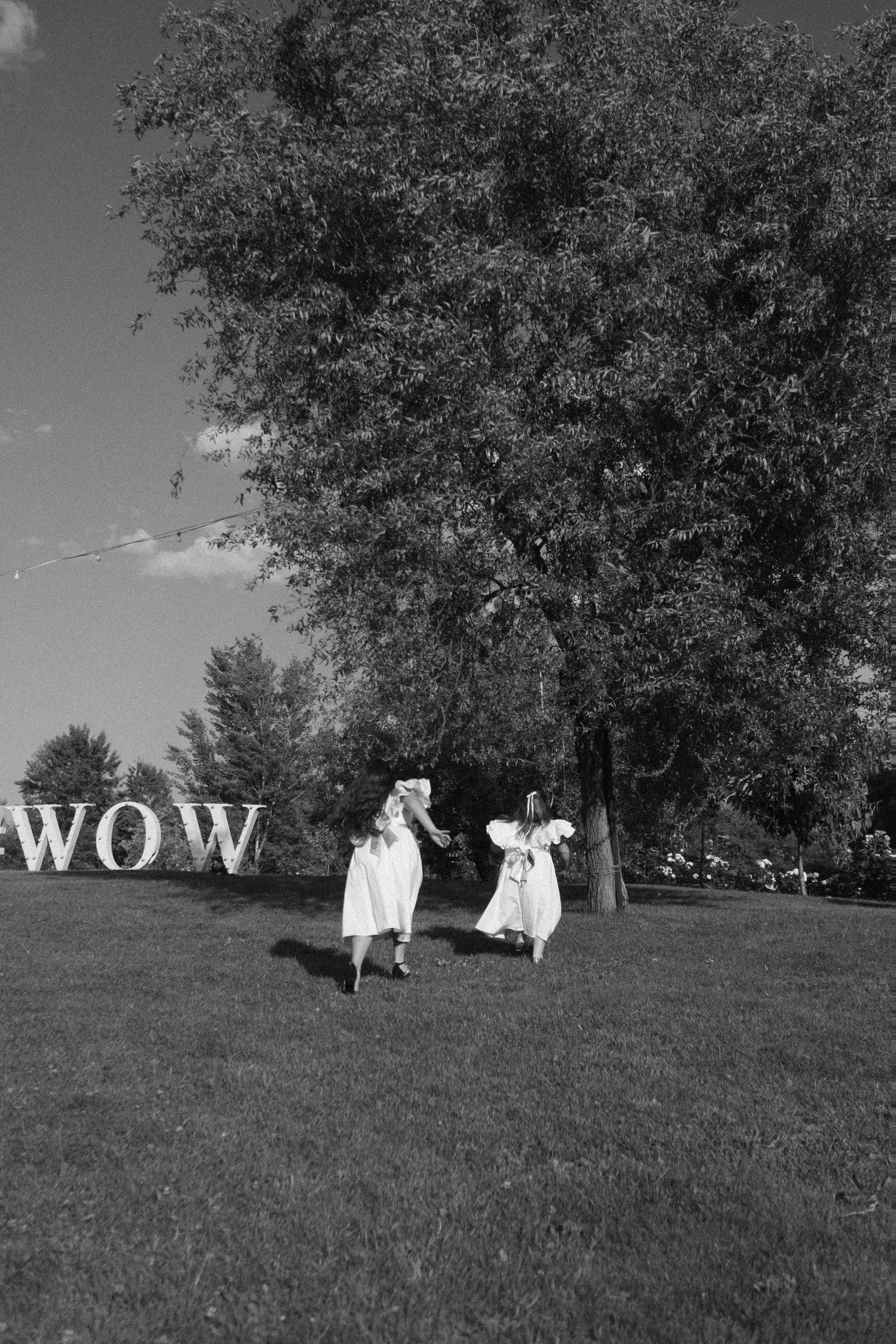 A large WOW sign on a lawn with a couple as tiny distant figures, black and white