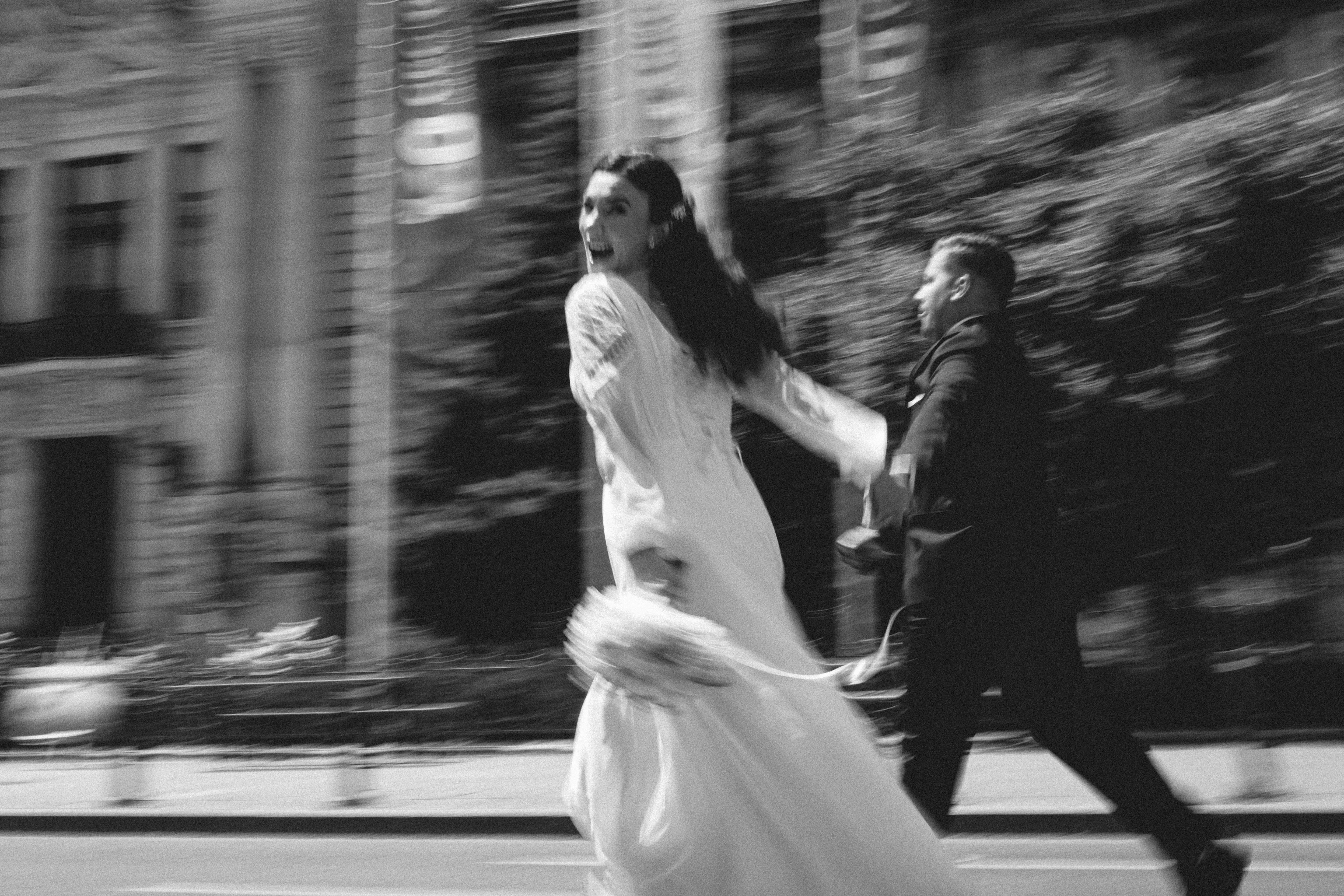 A couple running hand in hand down a city street in motion blur, black and white