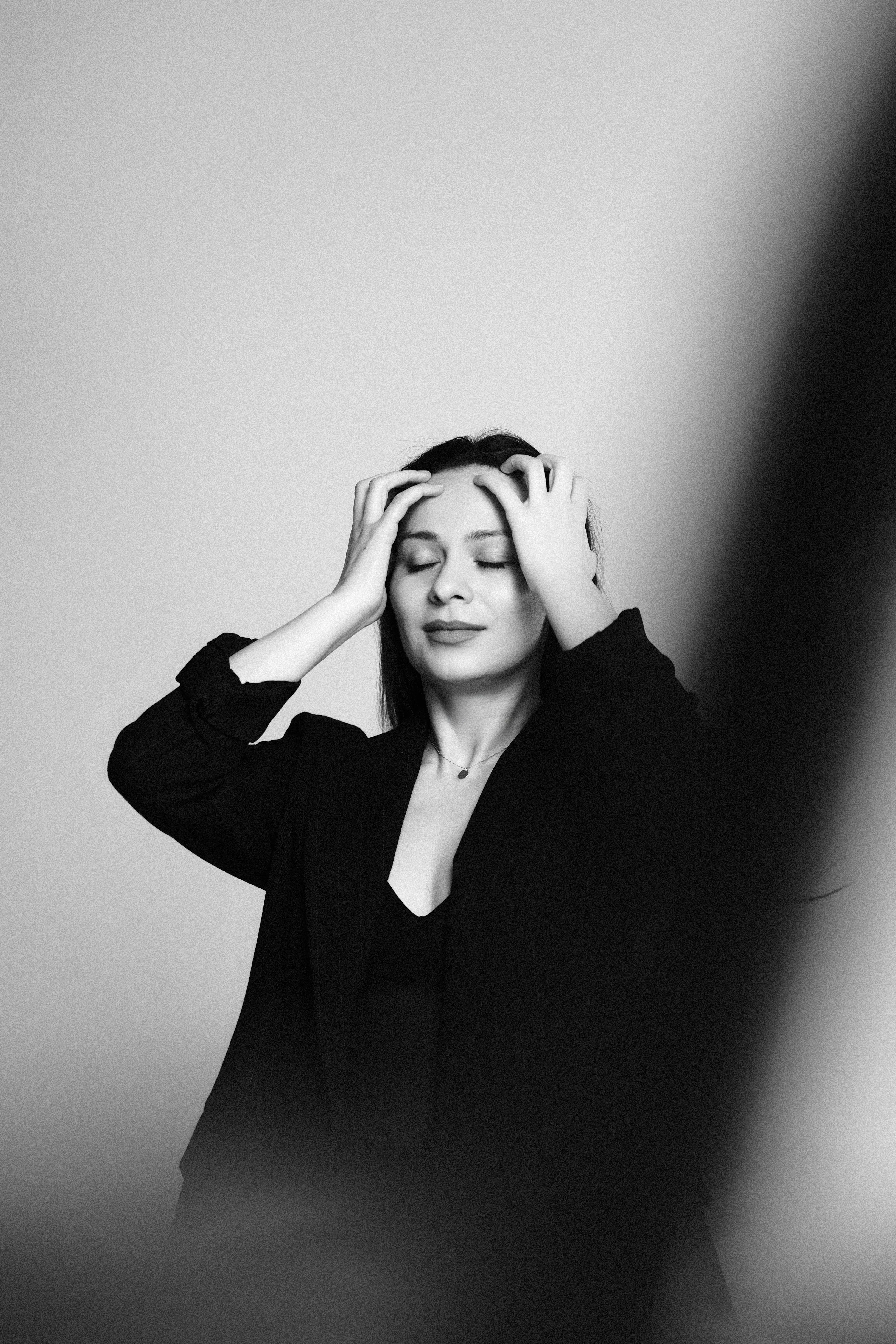 Black and white portrait of a woman with her hands in her hair, eyes closed