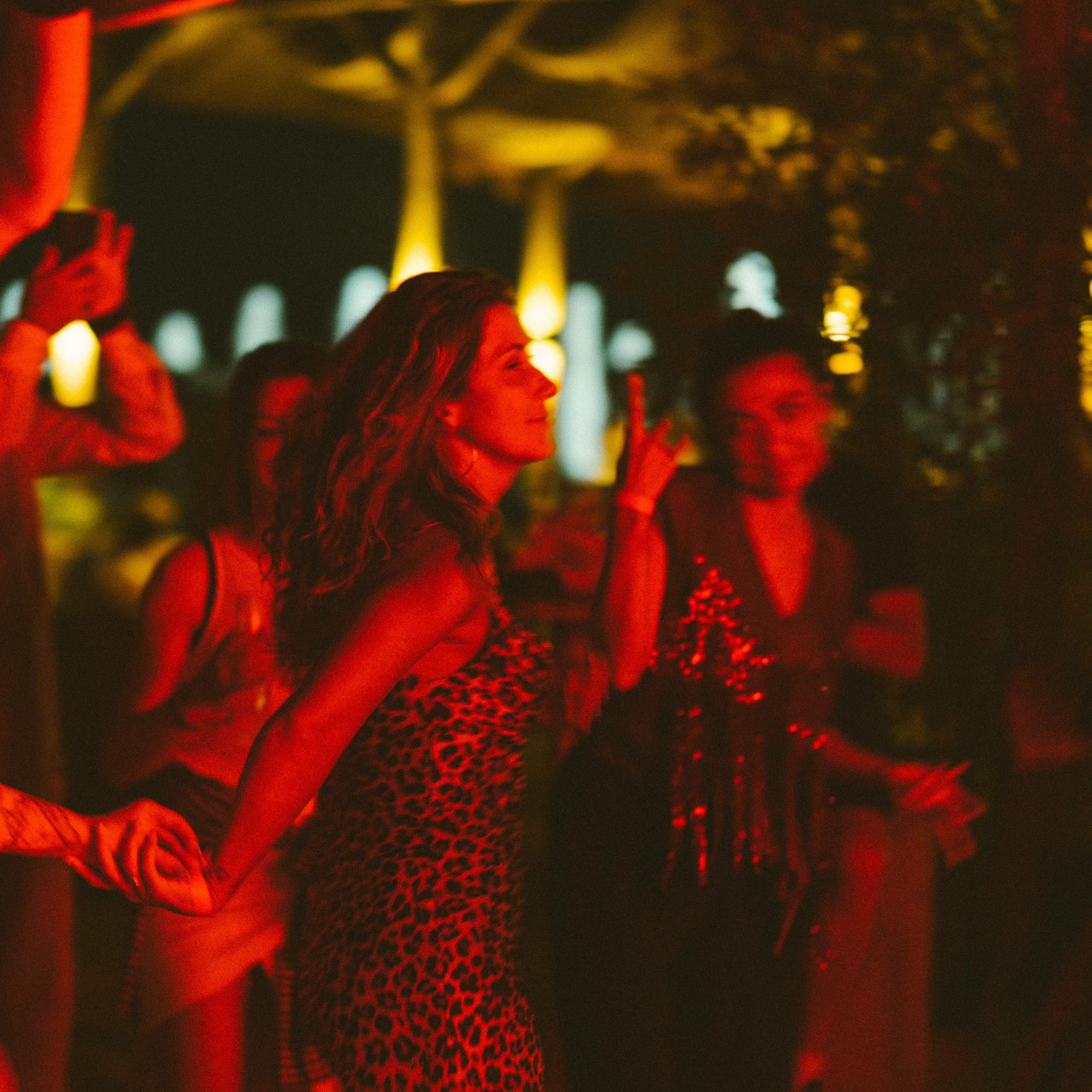 A woman dancing close to the camera, lit in red light