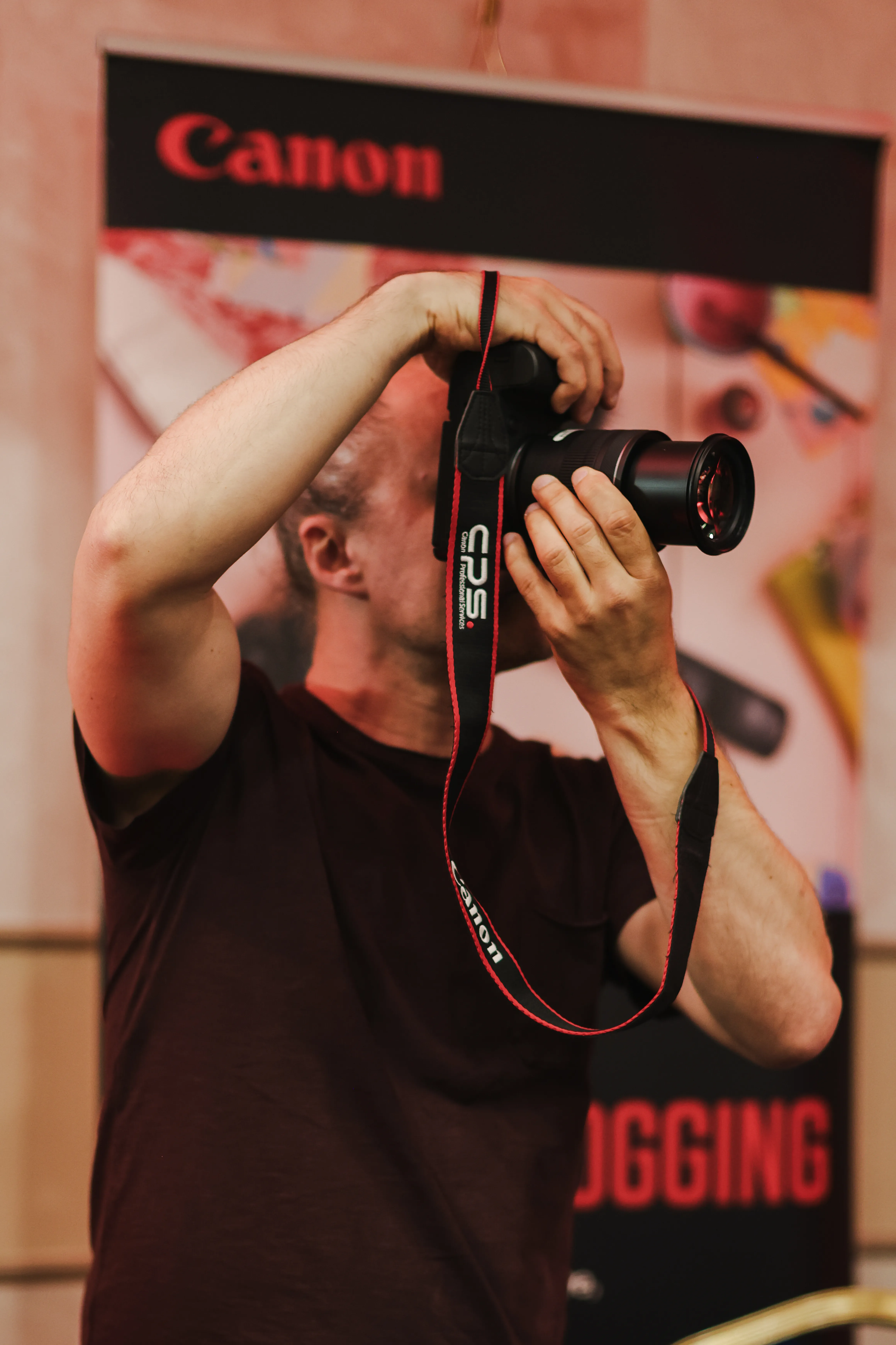An attendee photographing the Canon event banner with a long lens