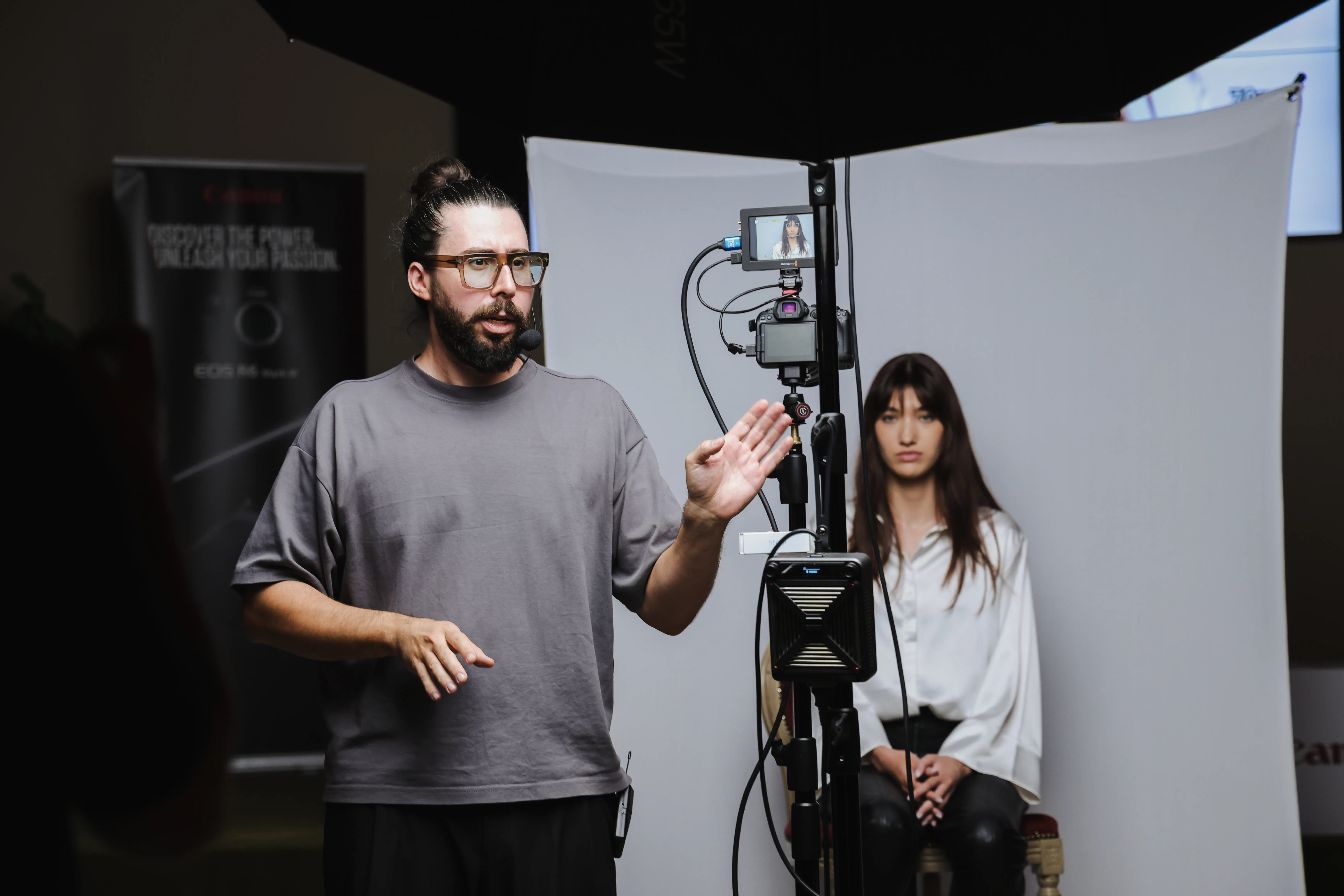 An instructor teaches a live portrait lighting demonstration on a Canon EOS R at a masterclass event