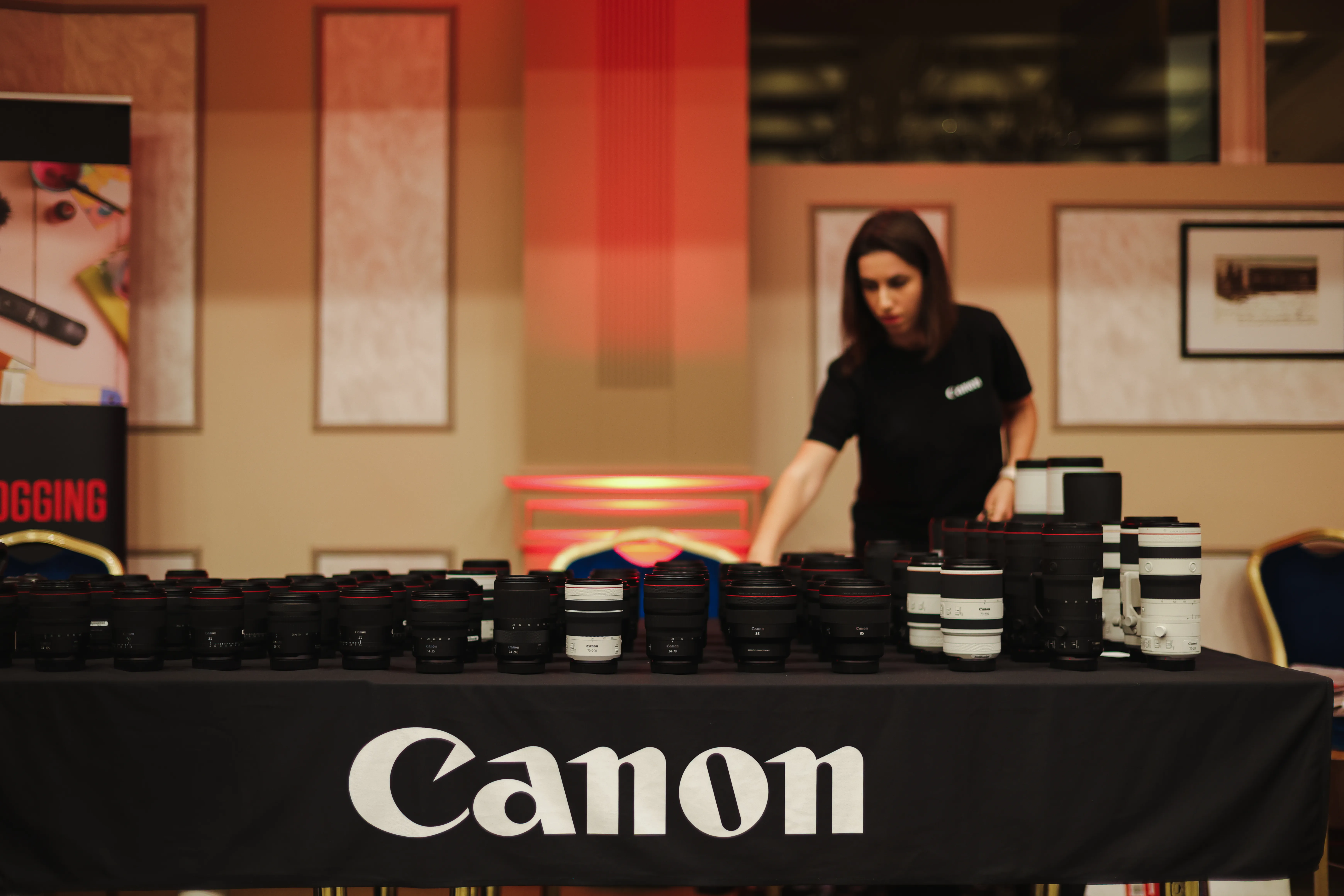 A woman arranging Canon merchandise on a branded table before the event