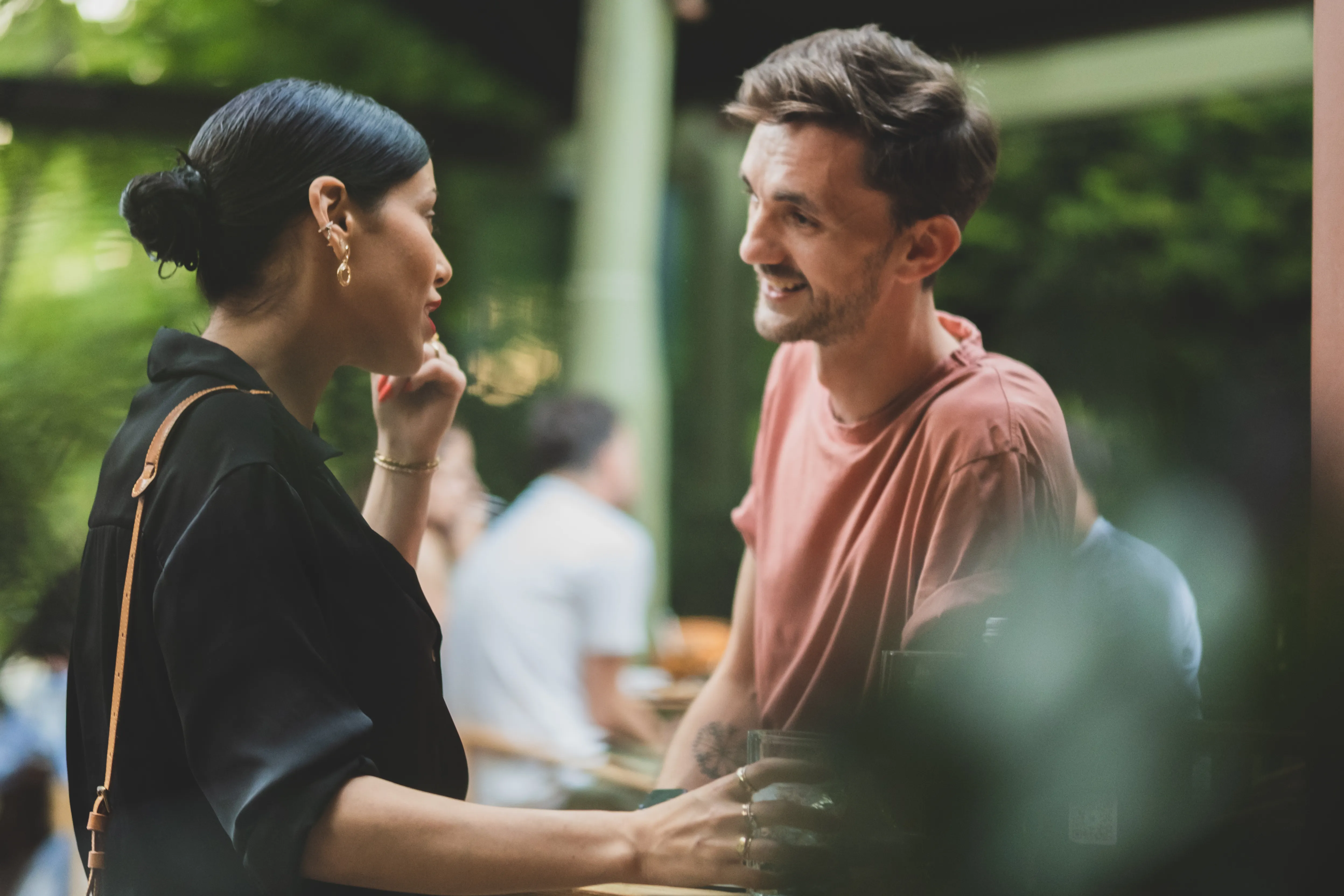 Two guests in warm, close conversation, string lights blurred behind them