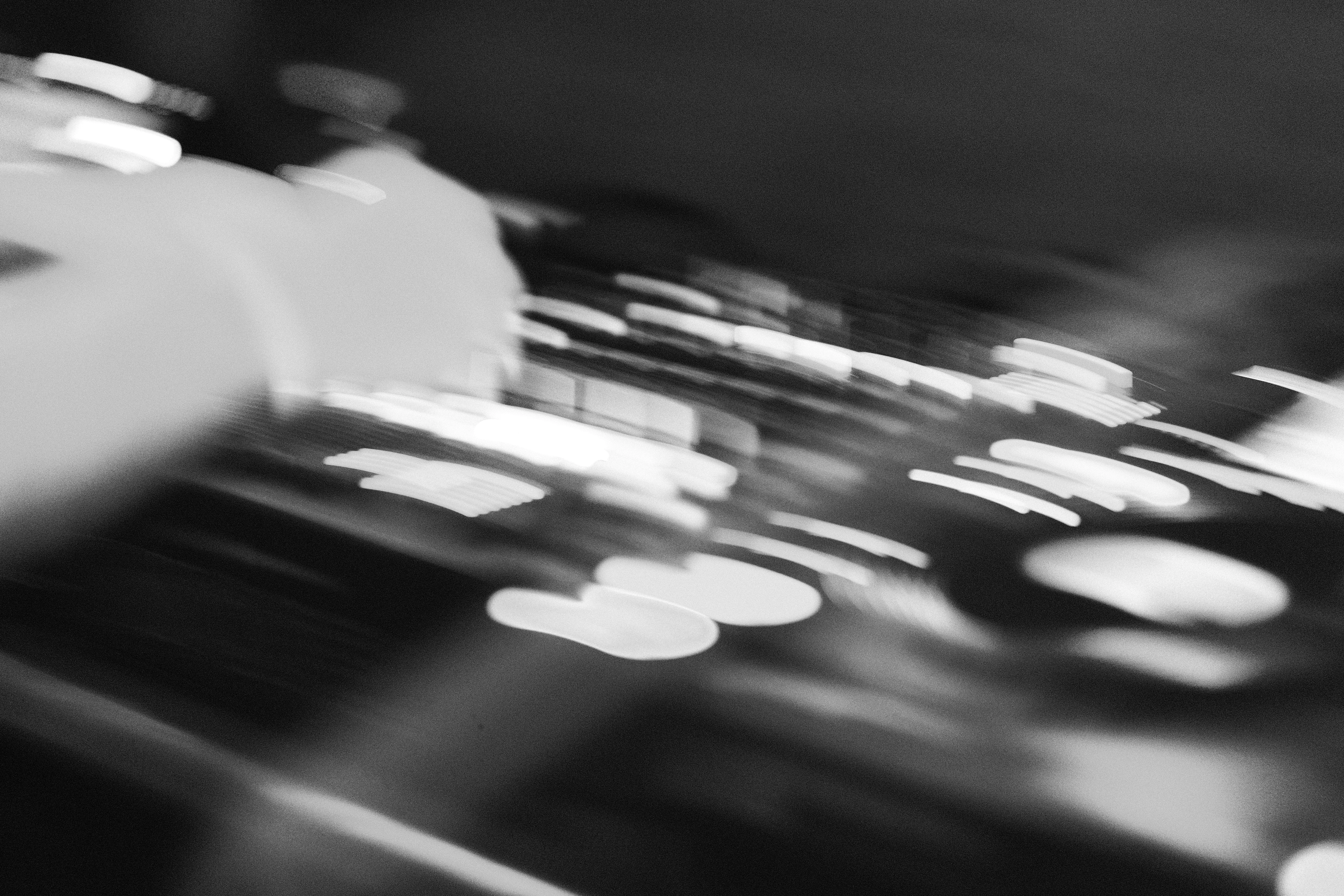 Motion-blurred hands cueing a record on a turntable, black and white