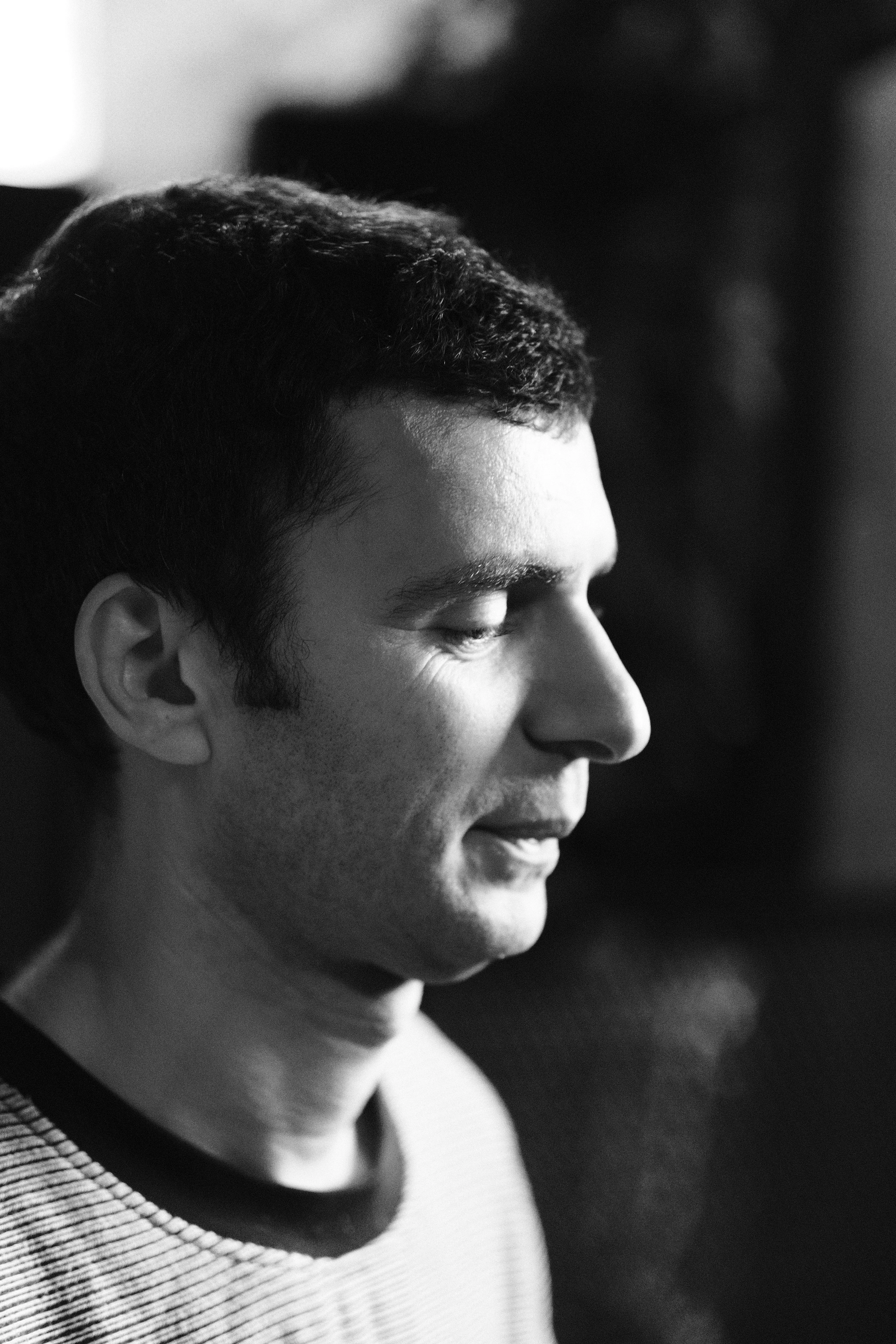 A man's profile in quiet stillness at the edge of the room, black and white