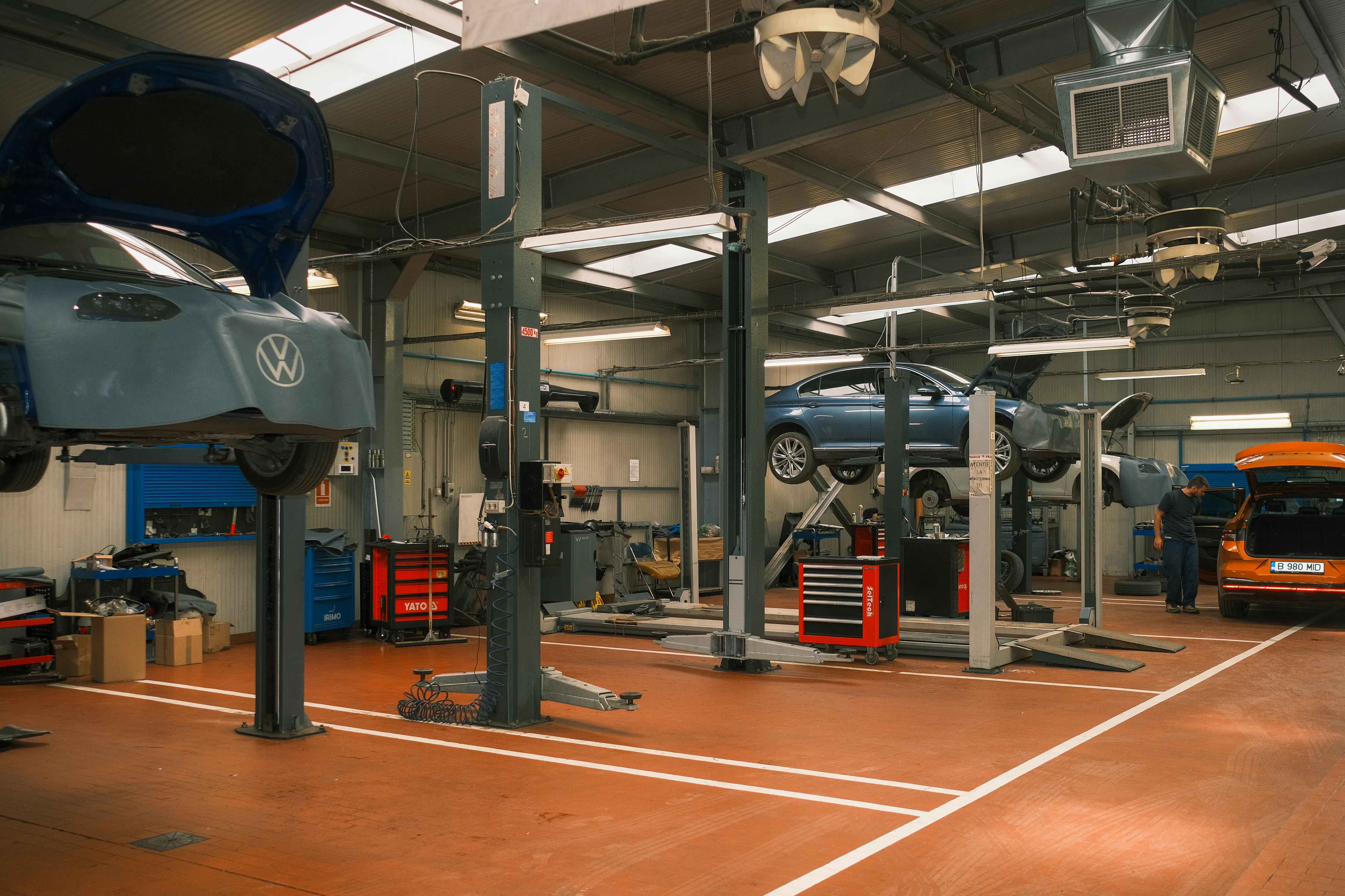 Service bay with cars raised on lifts, a technician working in the background
