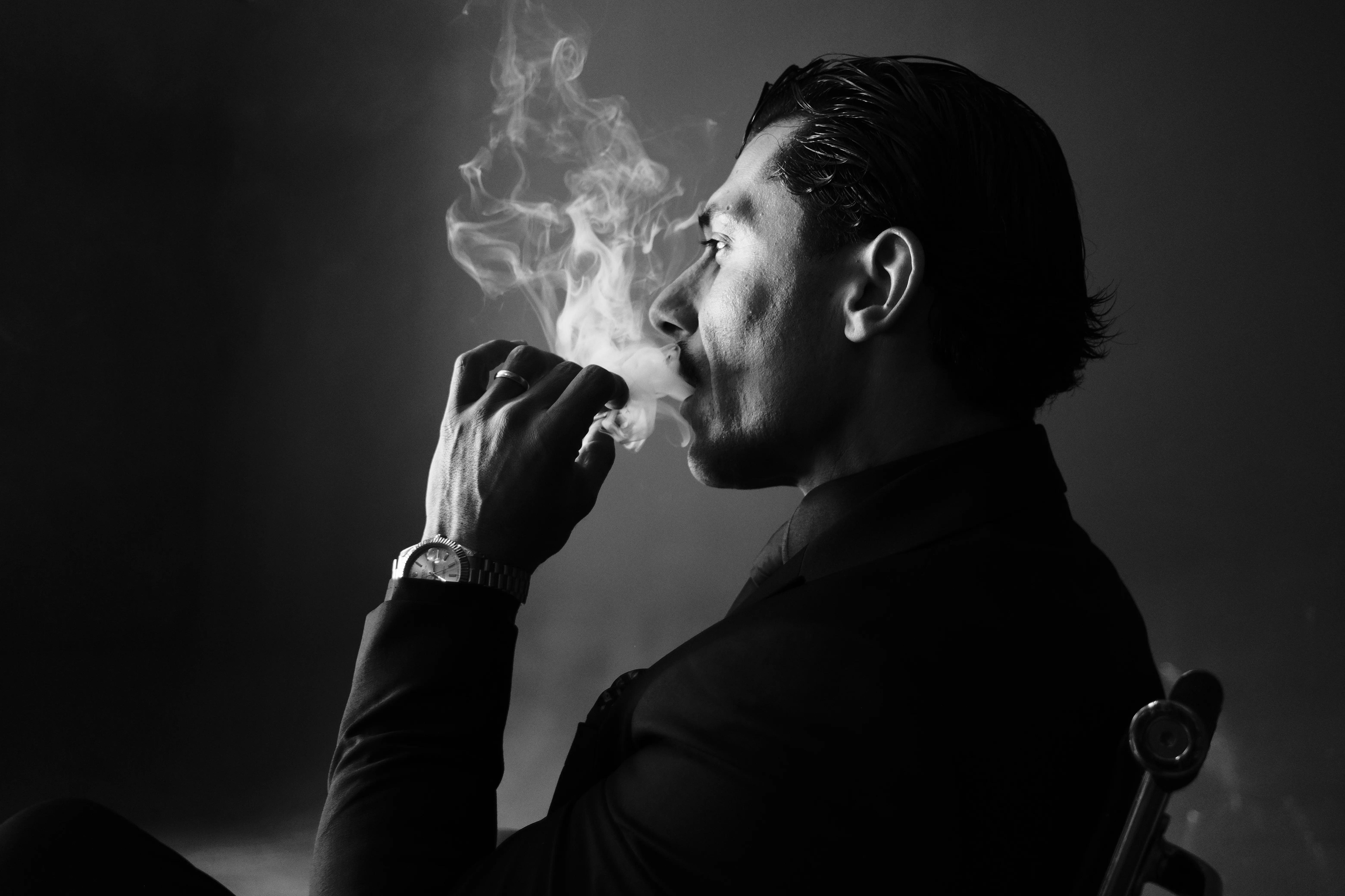 Profile portrait of a man exhaling smoke, dramatic black and white lighting