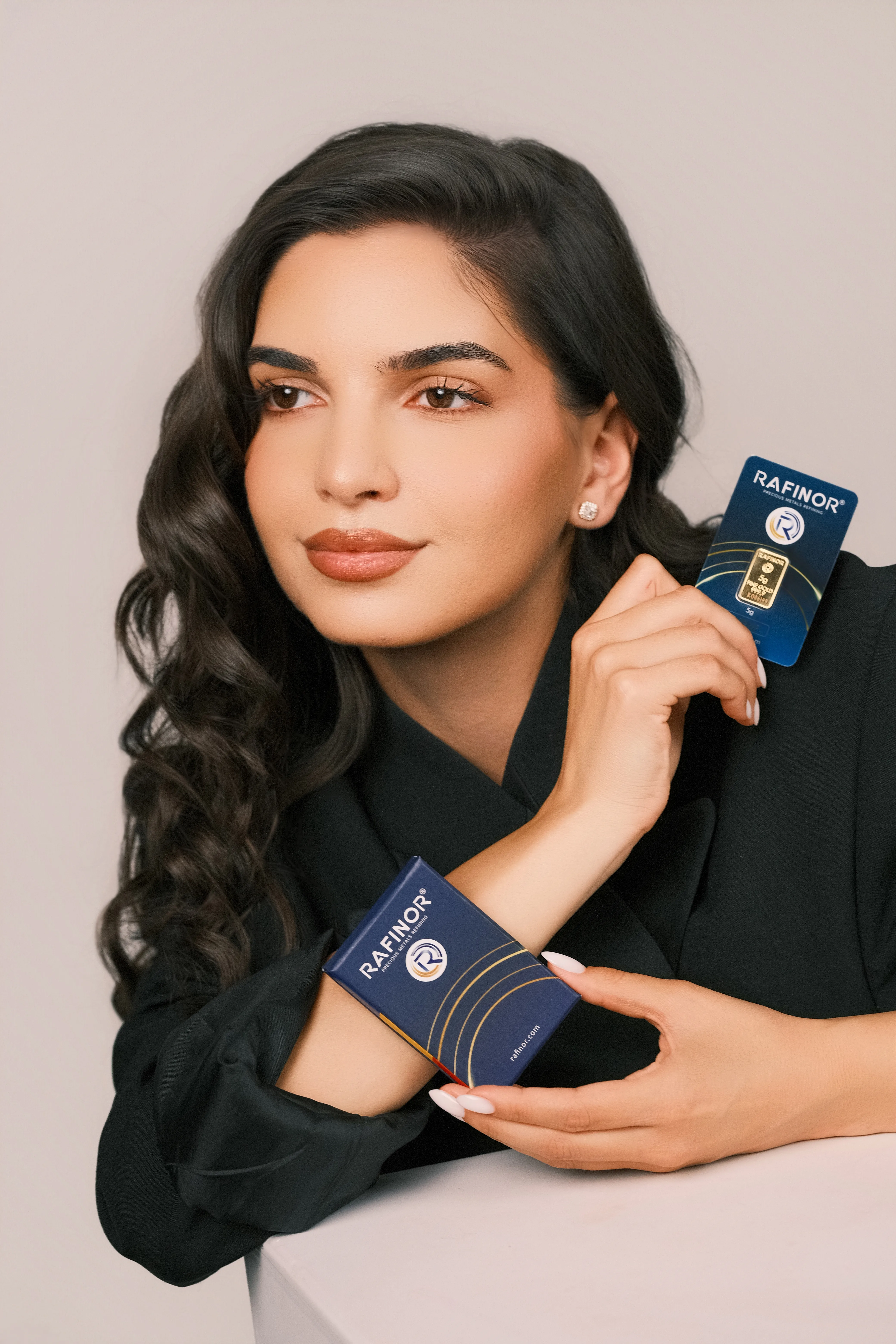 A woman holding a branded gold bar box against a black blazer