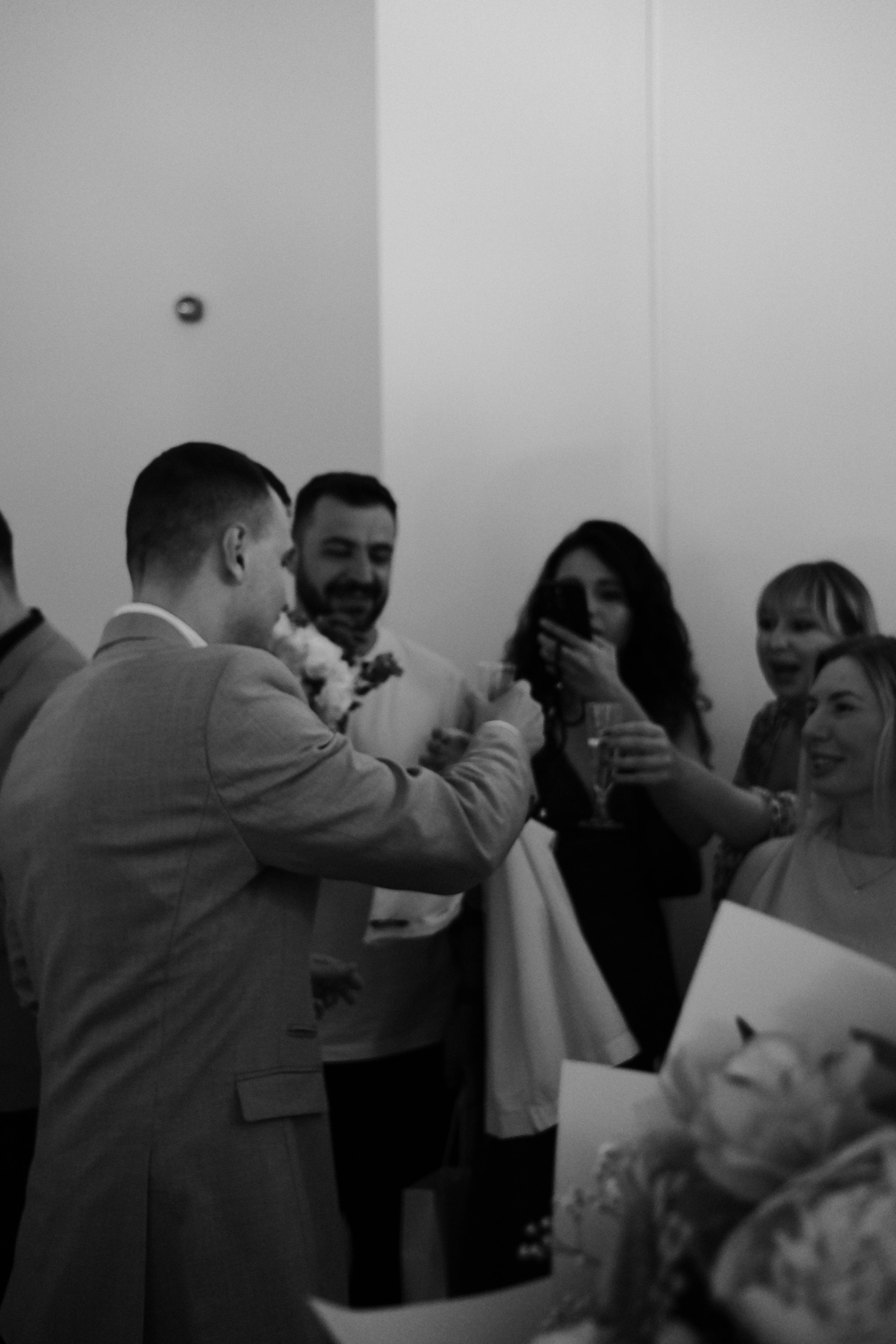 Guests raising a toast at the reception, candid, black and white