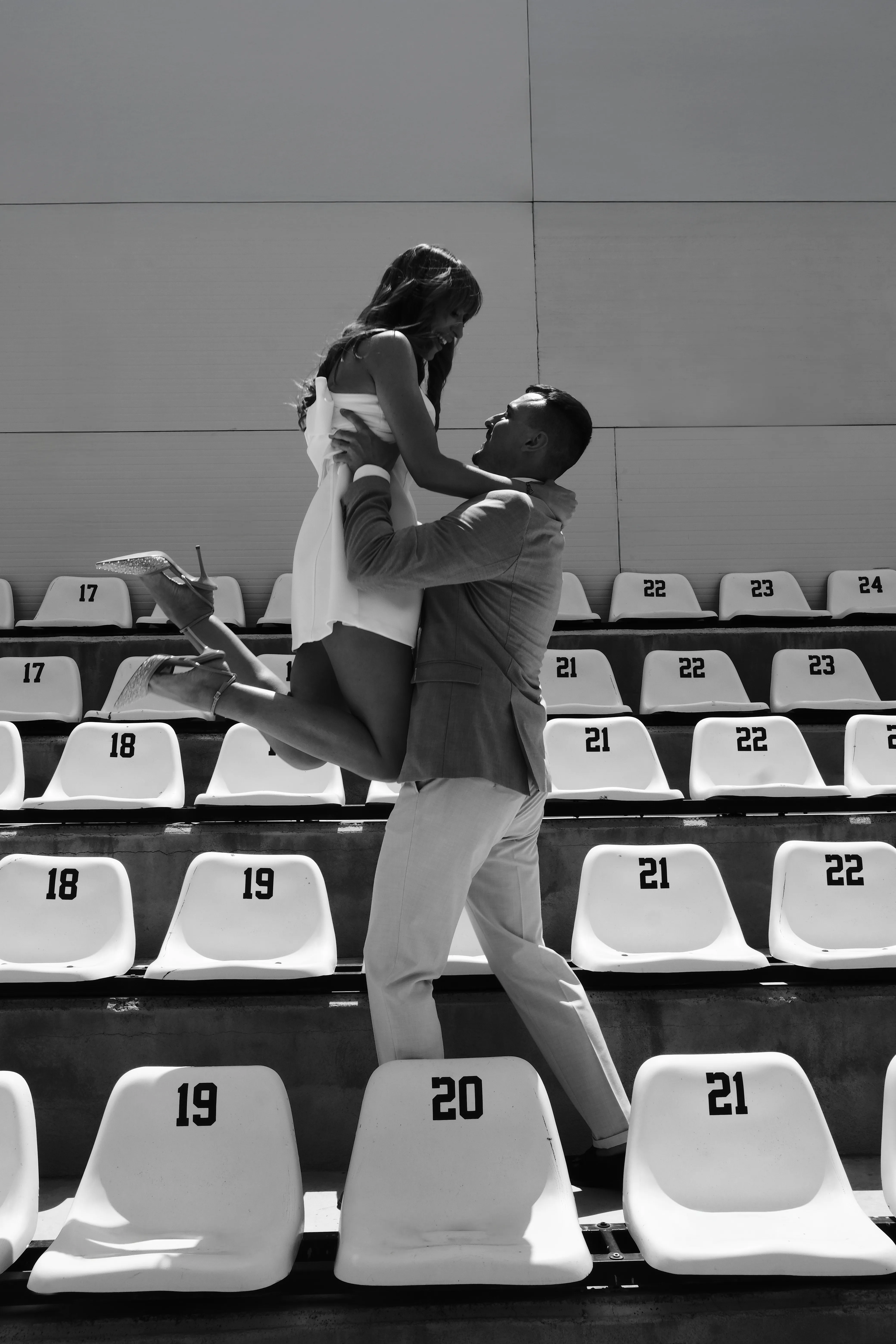 A groom lifting the bride in a piggyback, both laughing, black and white