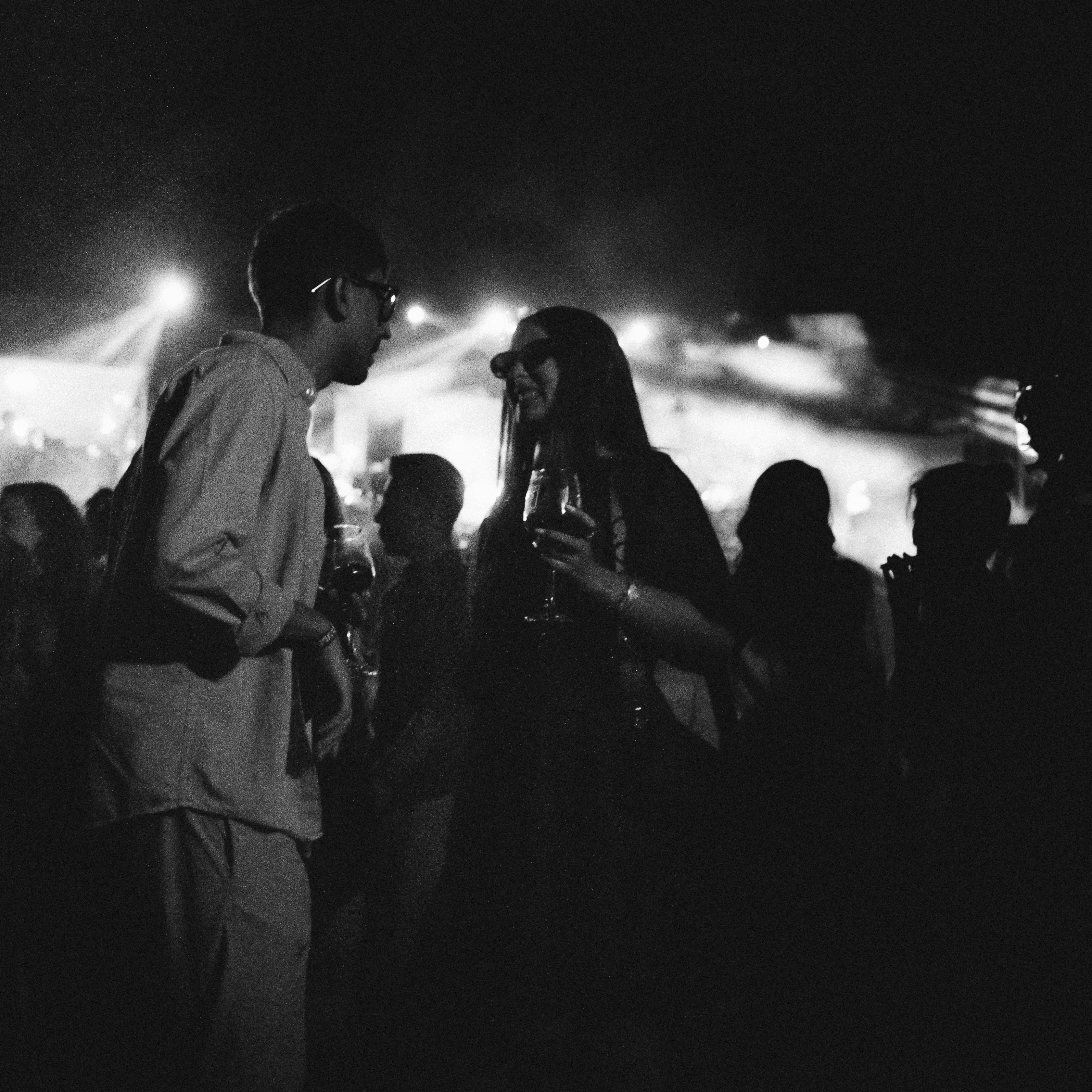 A crowd in silhouette under a single beam of light, black and white
