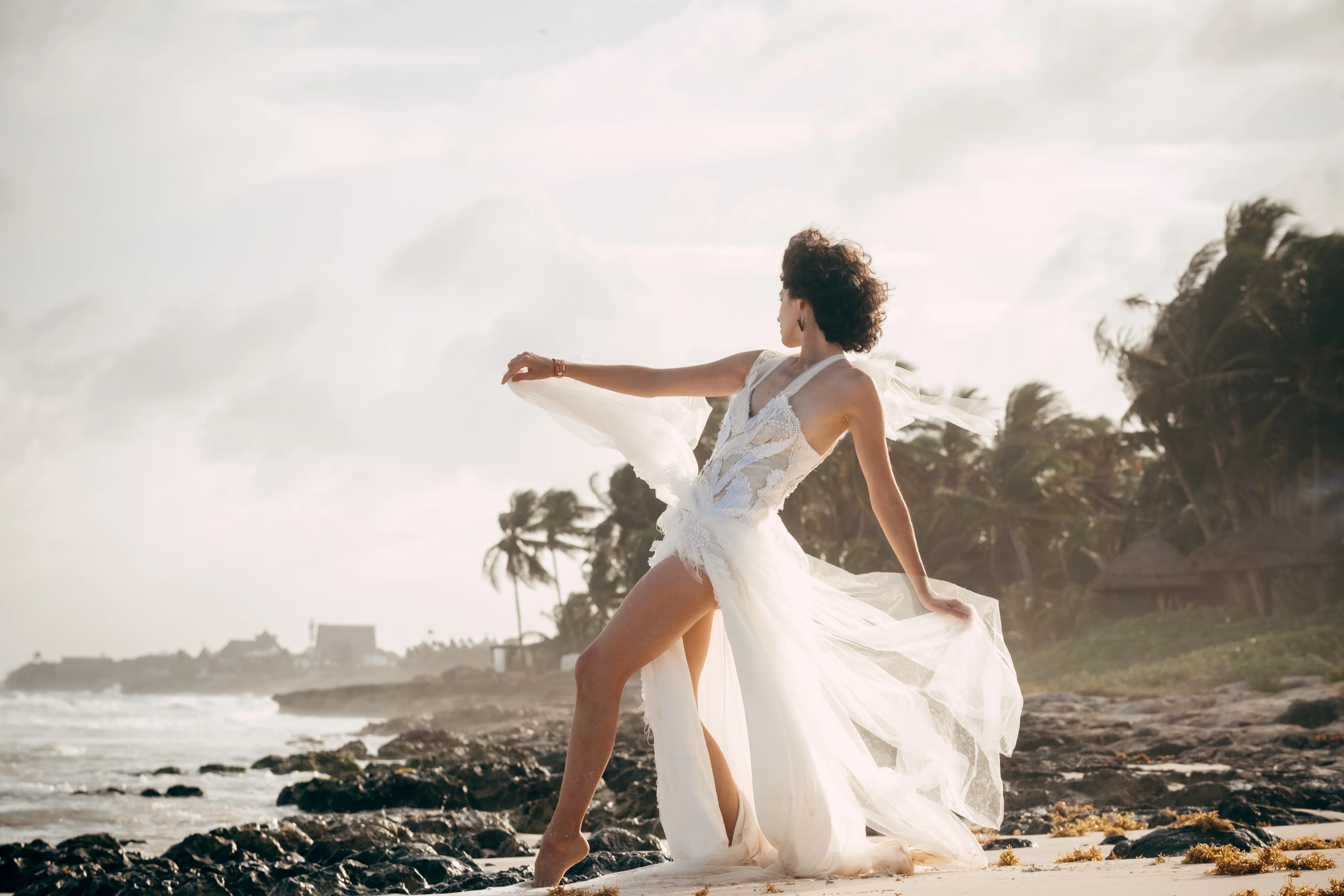 Silhouette of a woman dancing on a windswept beach, dress caught in motion