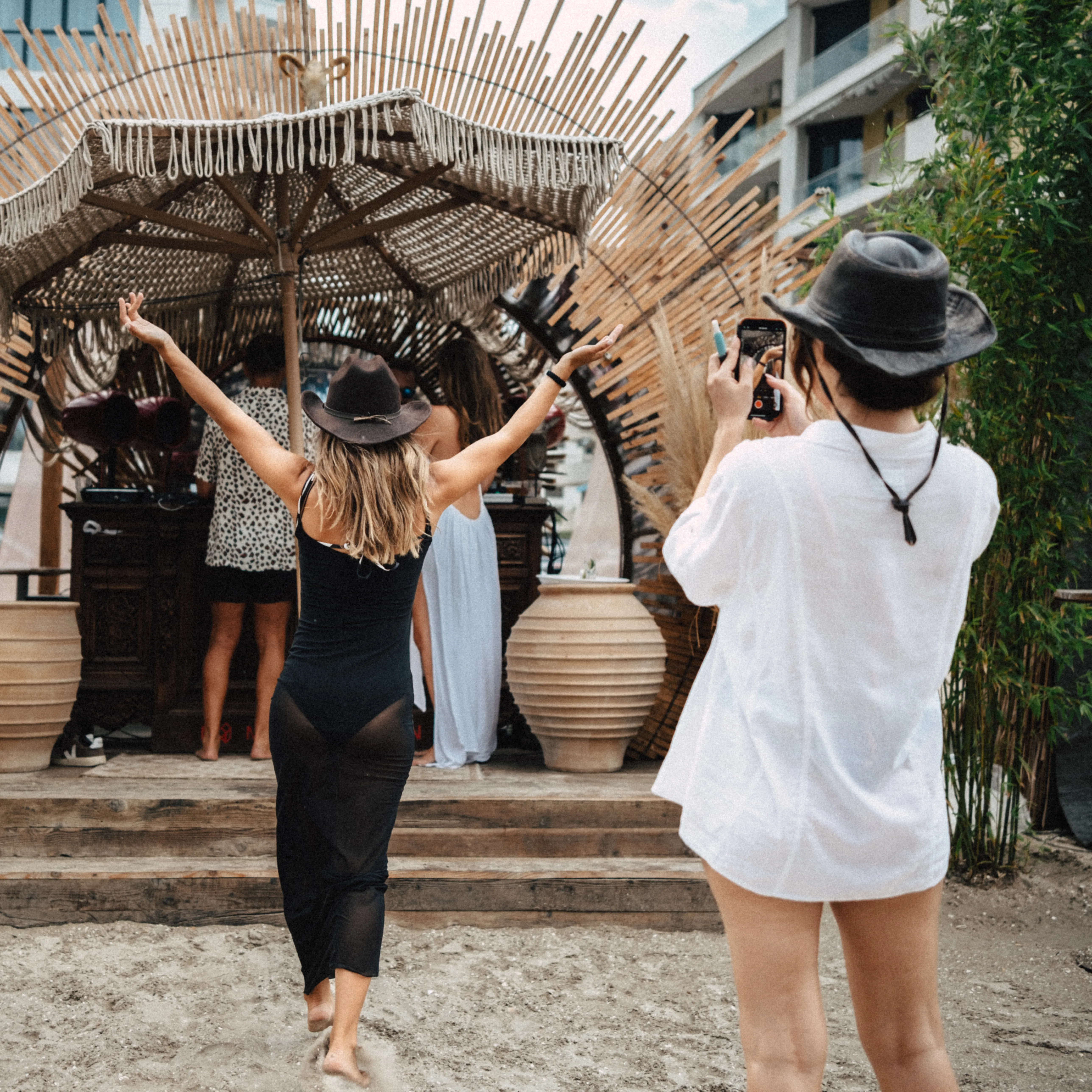 A group of women dancing with hands raised under a macrame umbrella in golden light