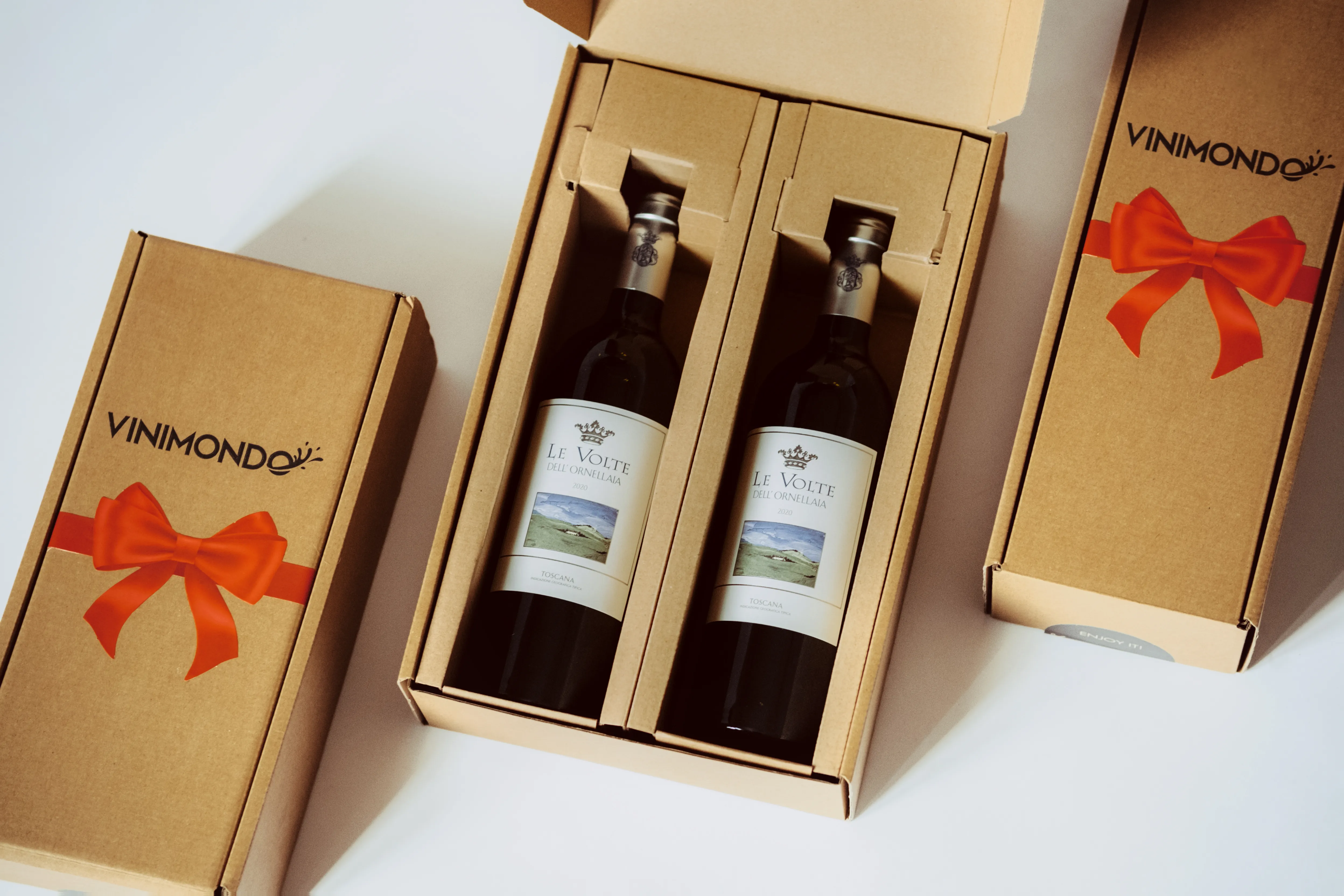 Two wine gift boxes tied with ribbon beside an open box showing two bottles