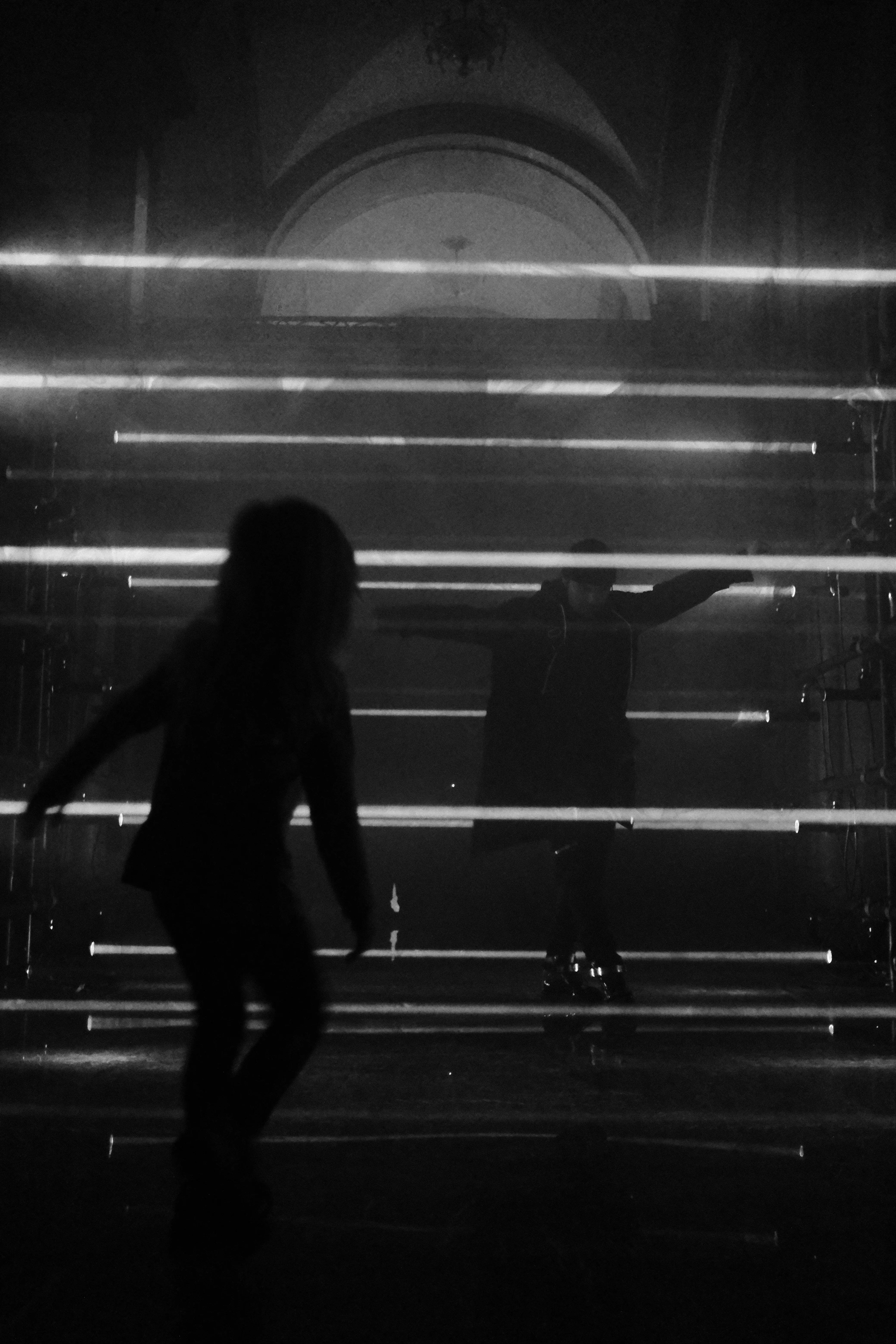 A silhouetted figure standing still against streaks of light and reflection, black and white