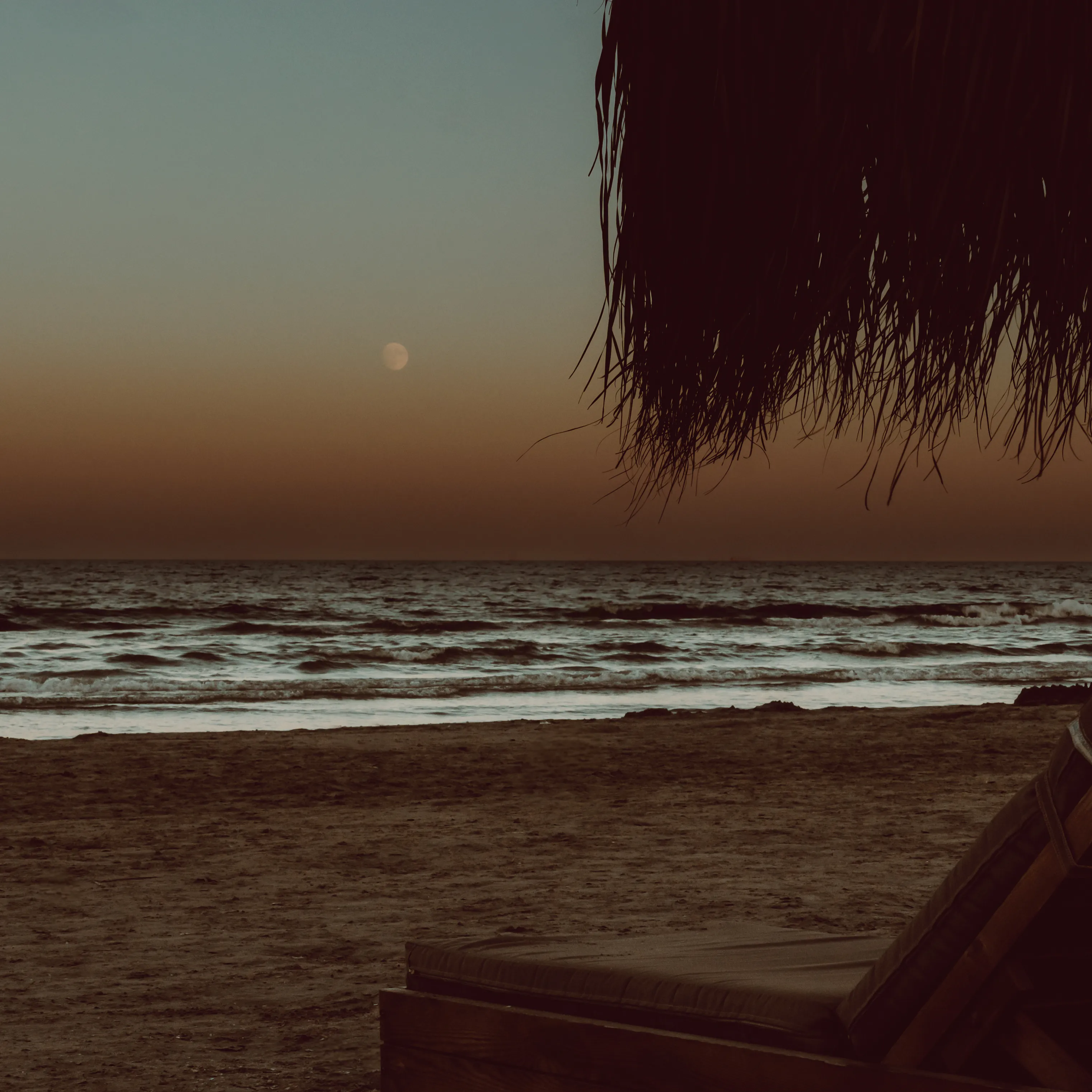 The moon rising over a dark, calm sea