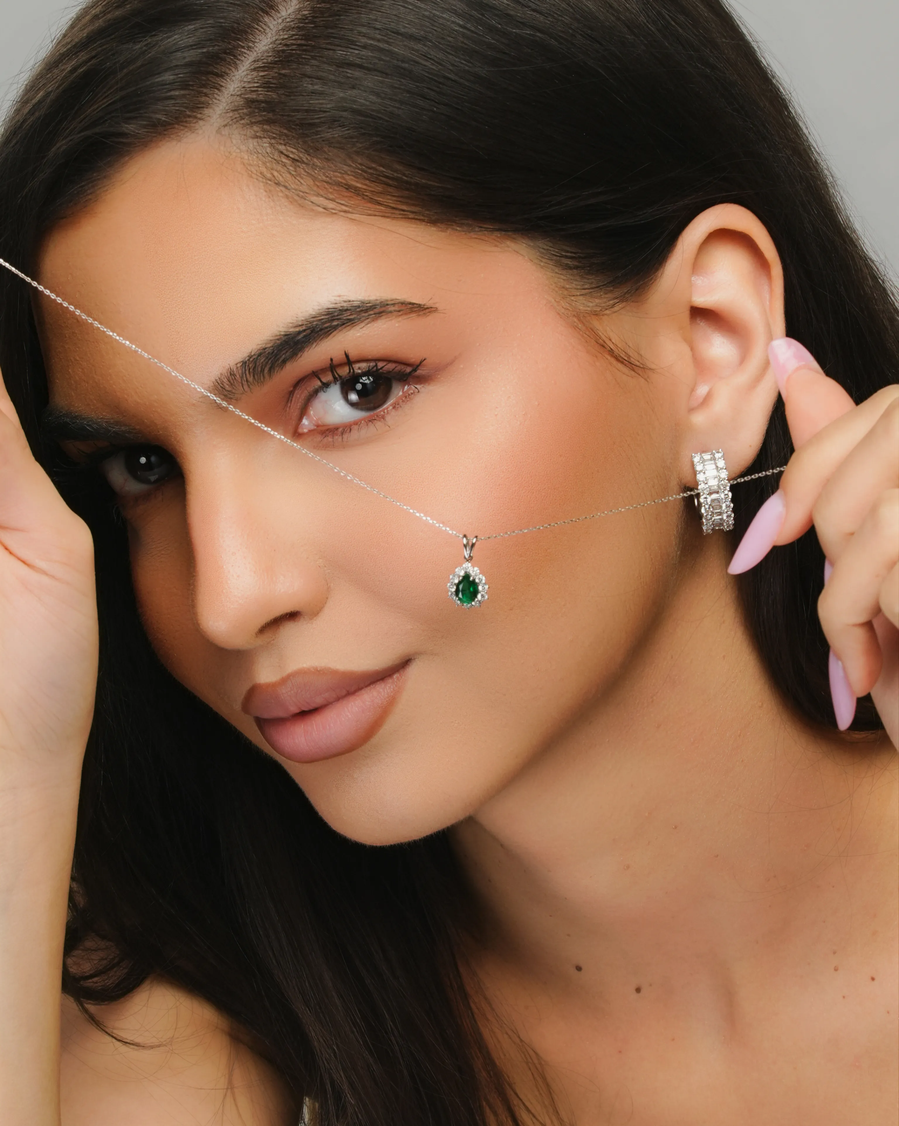 Extreme close-up beauty shot of an emerald pendant and diamond hoop earring