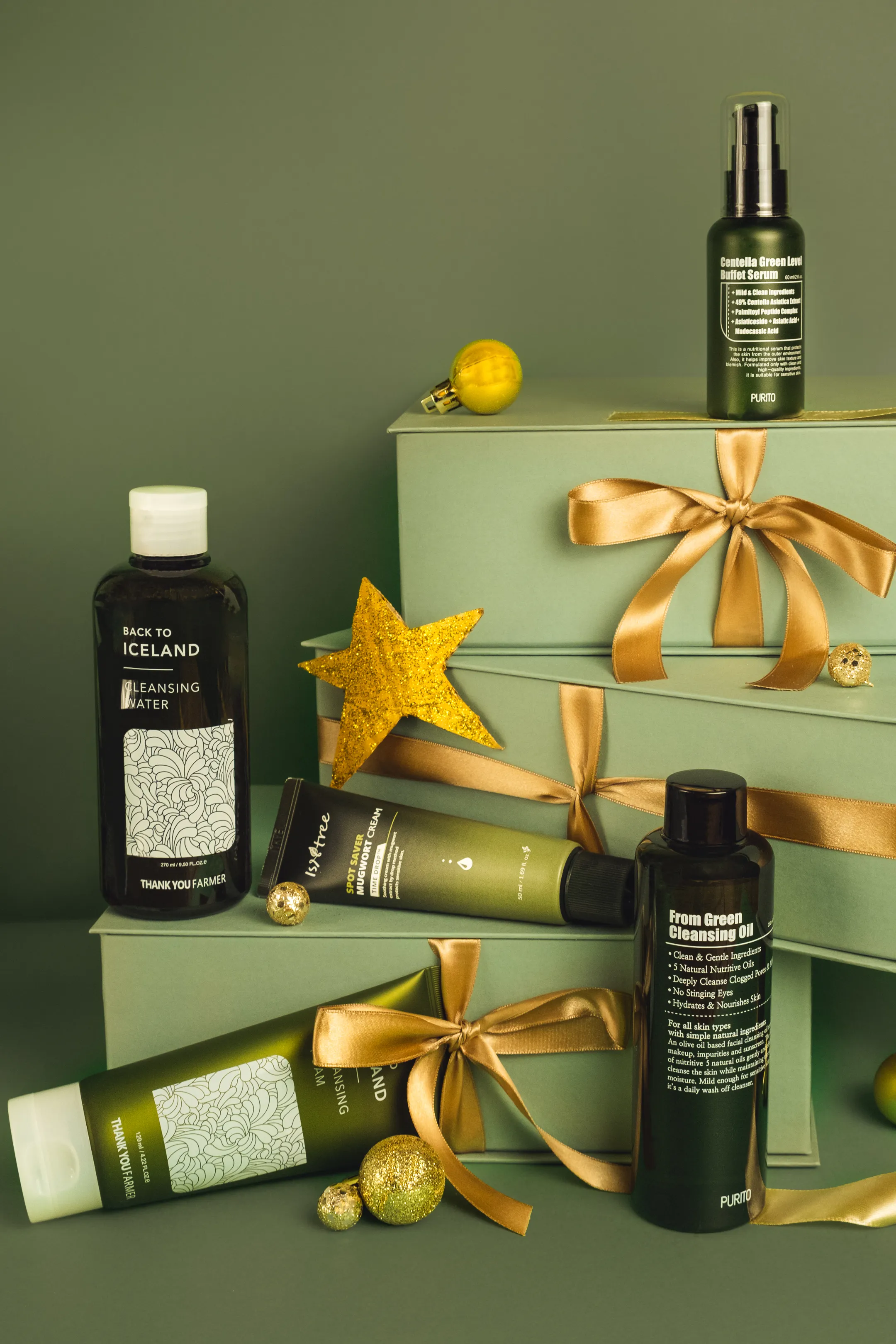 A green-and-gold skincare gift set staged on boxes with ornaments