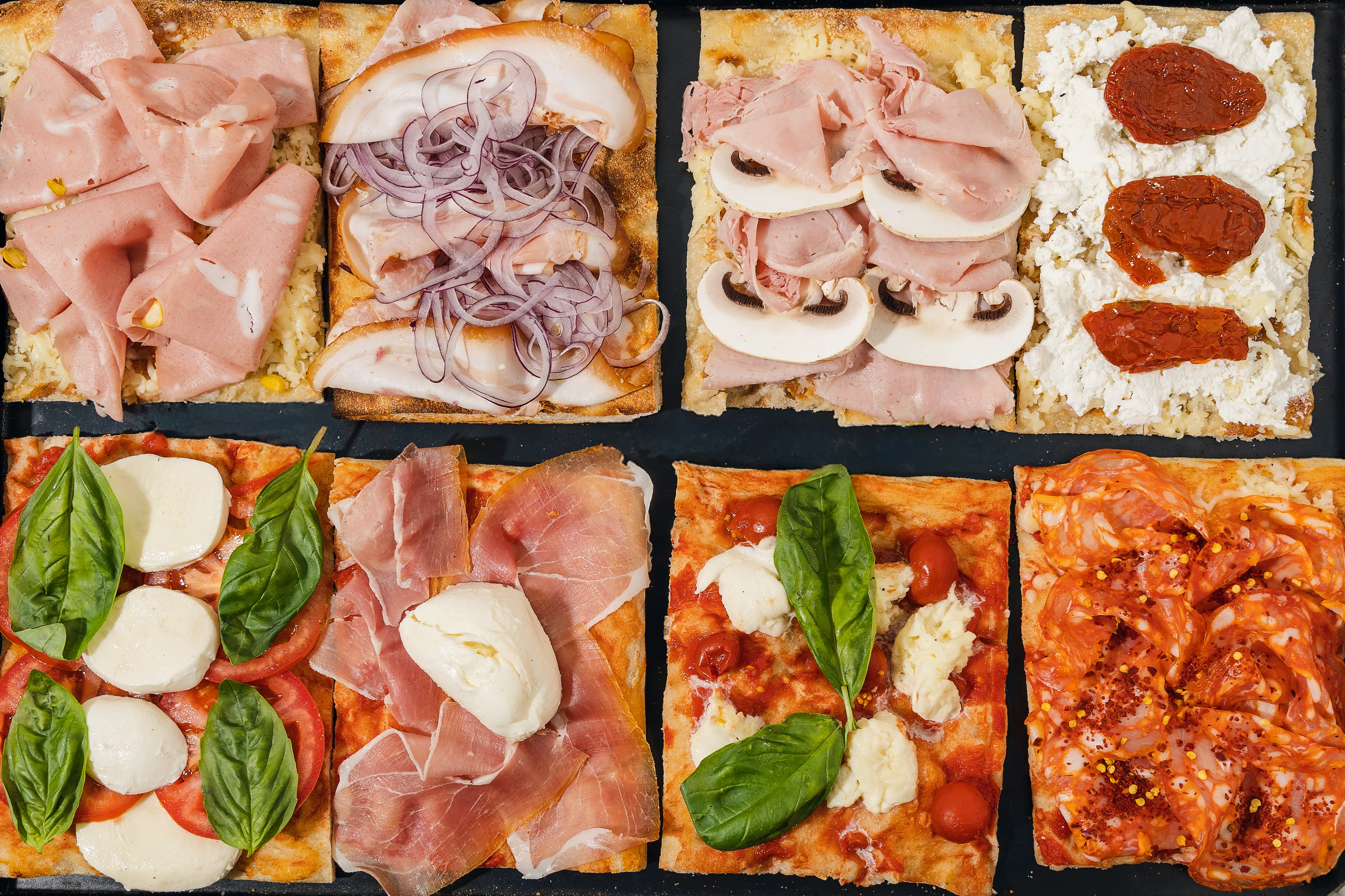 A grid of eight flatbread varieties, each topped differently — ham, turkey, mushroom, mozzarella, prosciutto, salami