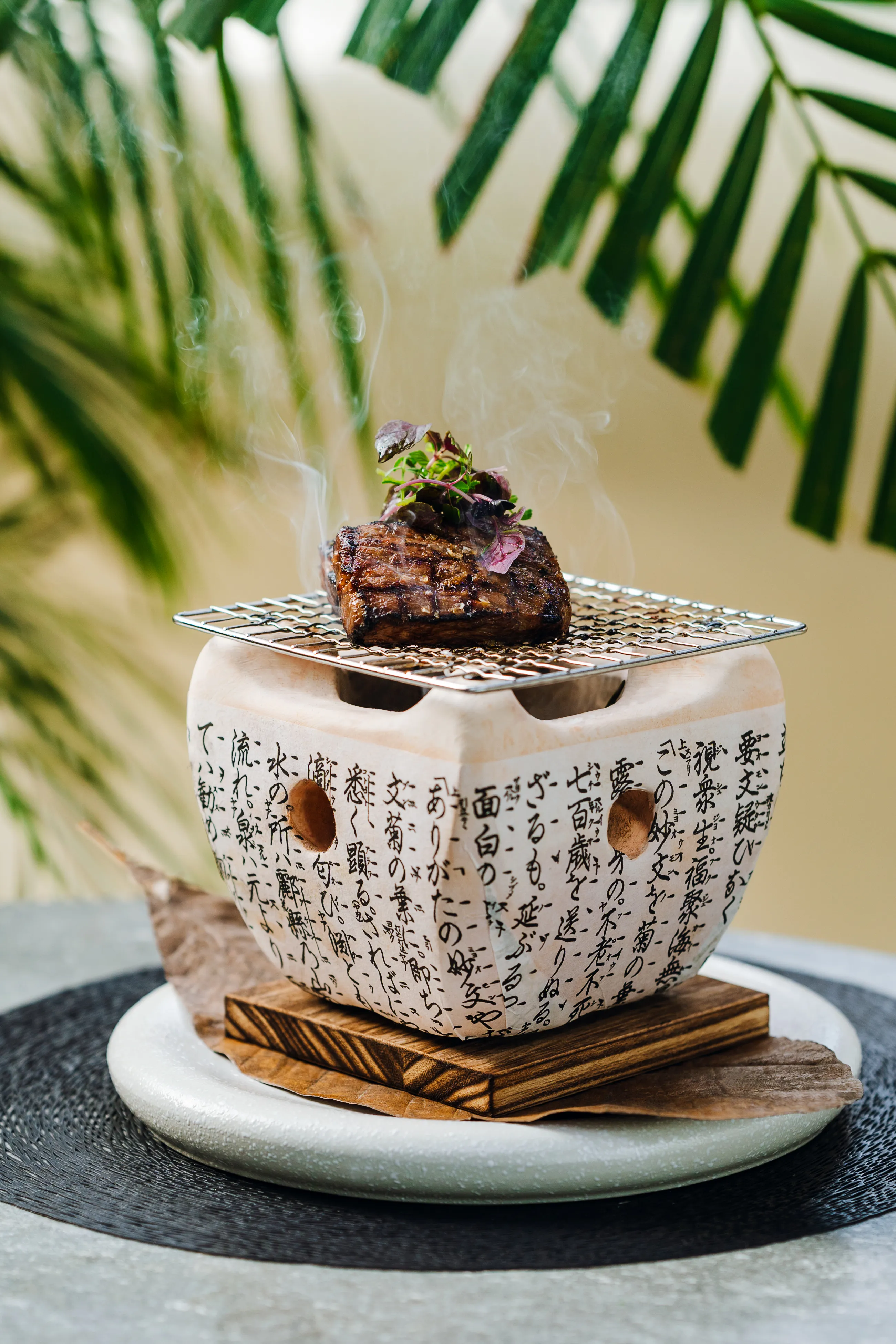 A single dessert plated on a decorative ceramic stand against a palm leaf backdrop