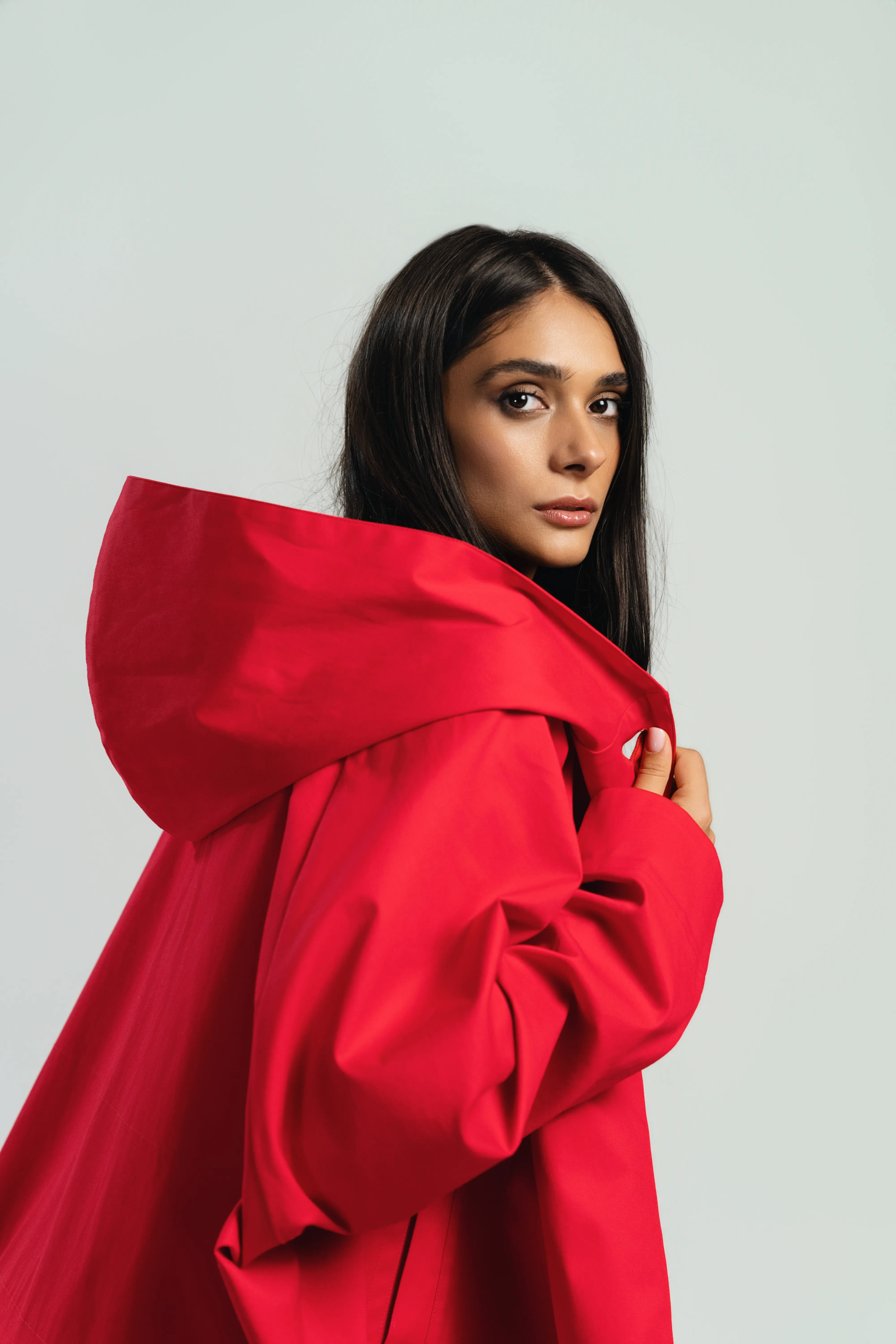 Model in a cropped green wool peacoat and pleated skirt, studio backdrop