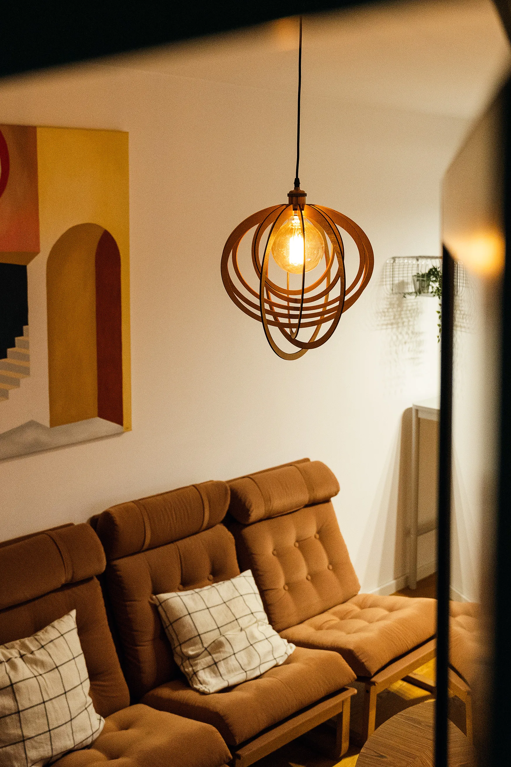 A decorative wood-slat pendant lamp glowing warmly in a living room