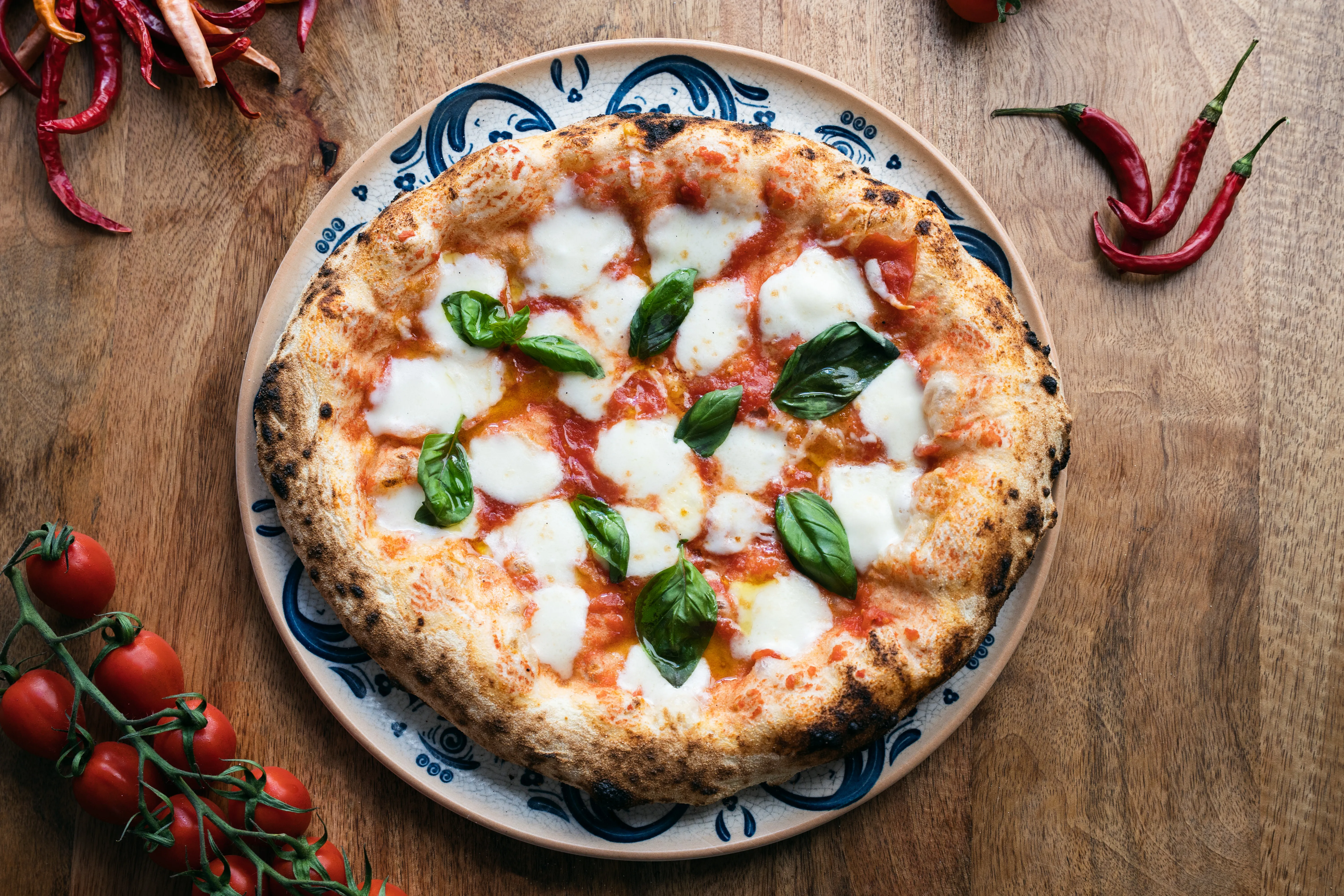 Overhead view of a wood-fired margherita pizza with fresh basil