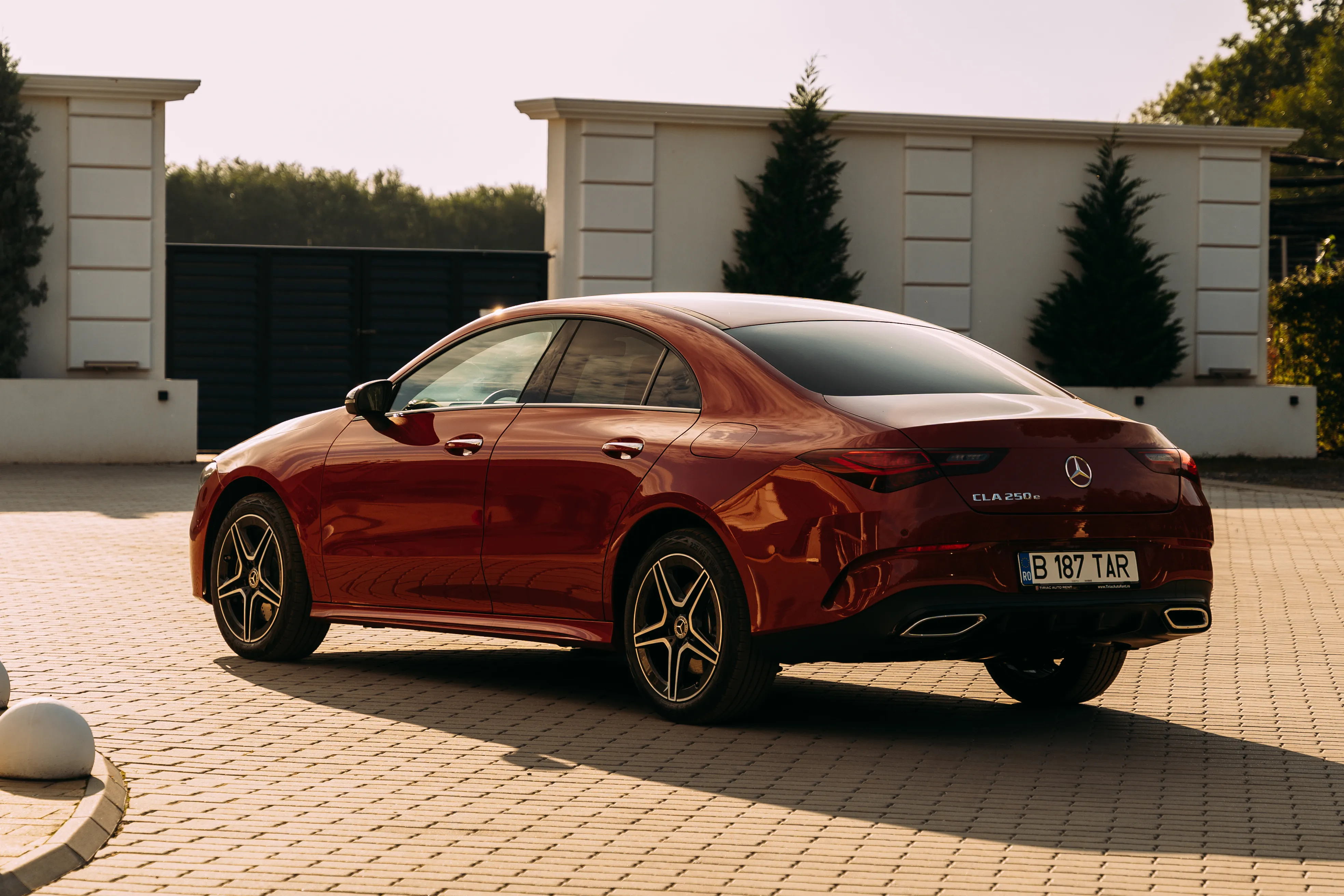 Mercedes-Benz CLA parked in a formal garden, low three-quarter angle with a mirrored sphere sculpture behind it