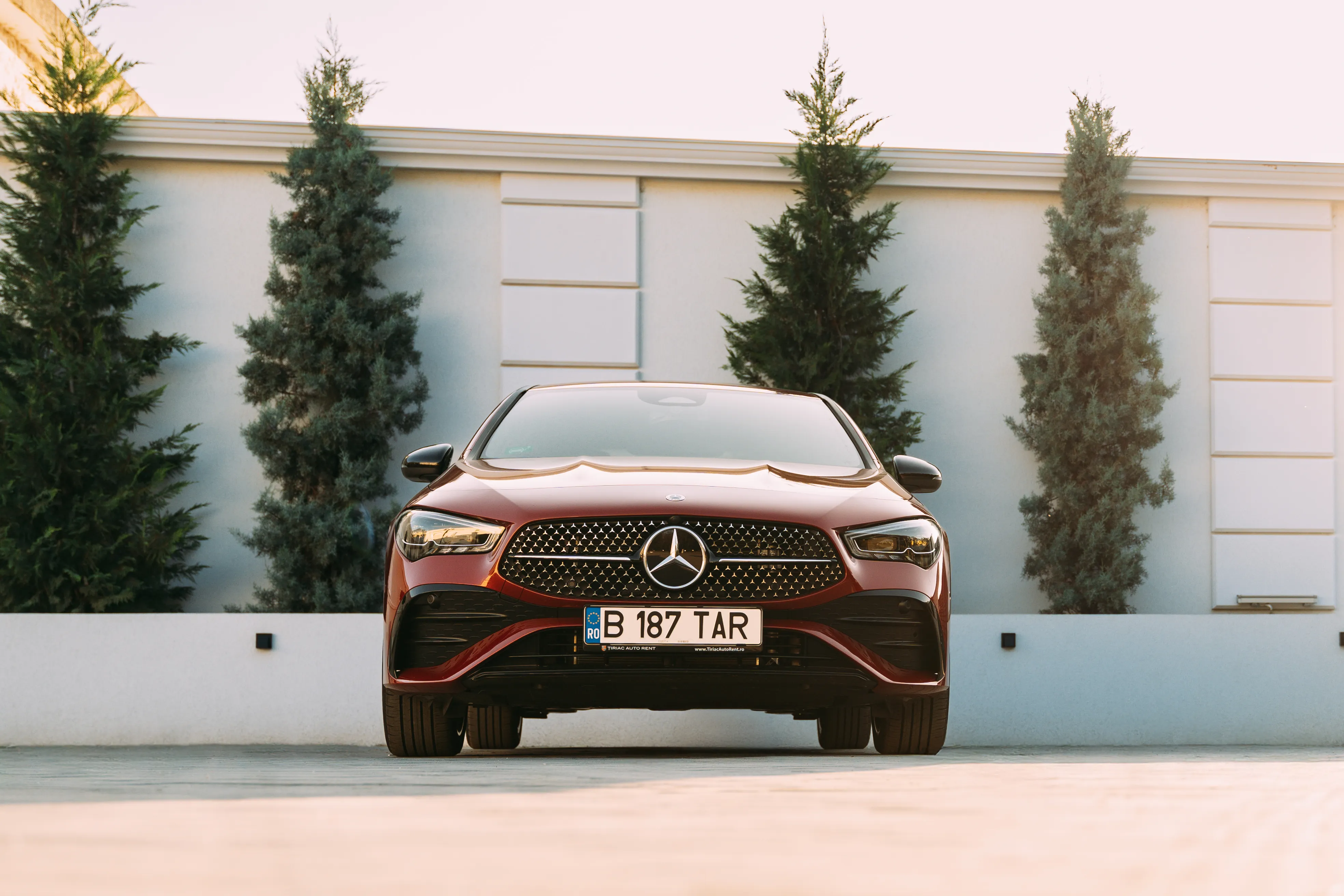 Red CLA, rear three-quarter angle, golden-hour light against a pale villa wall