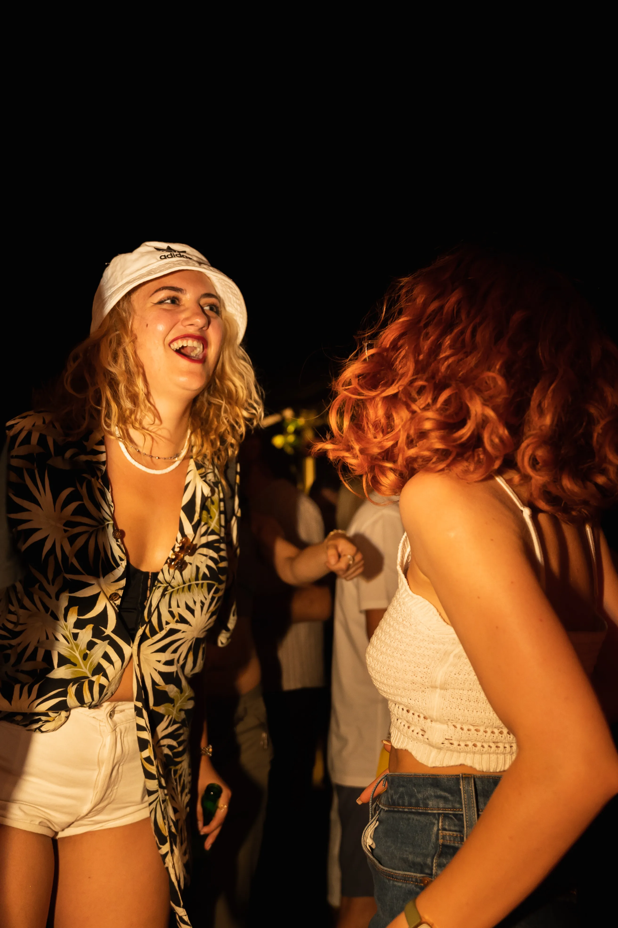 Two women laughing together at a golden-hour gathering
