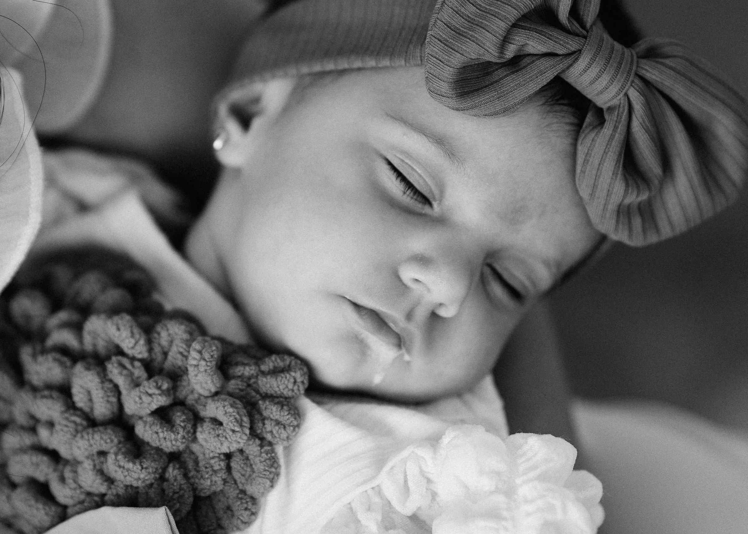 Black and white close-up of baby Beatrice Gabriela asleep, a knitted bow on her head