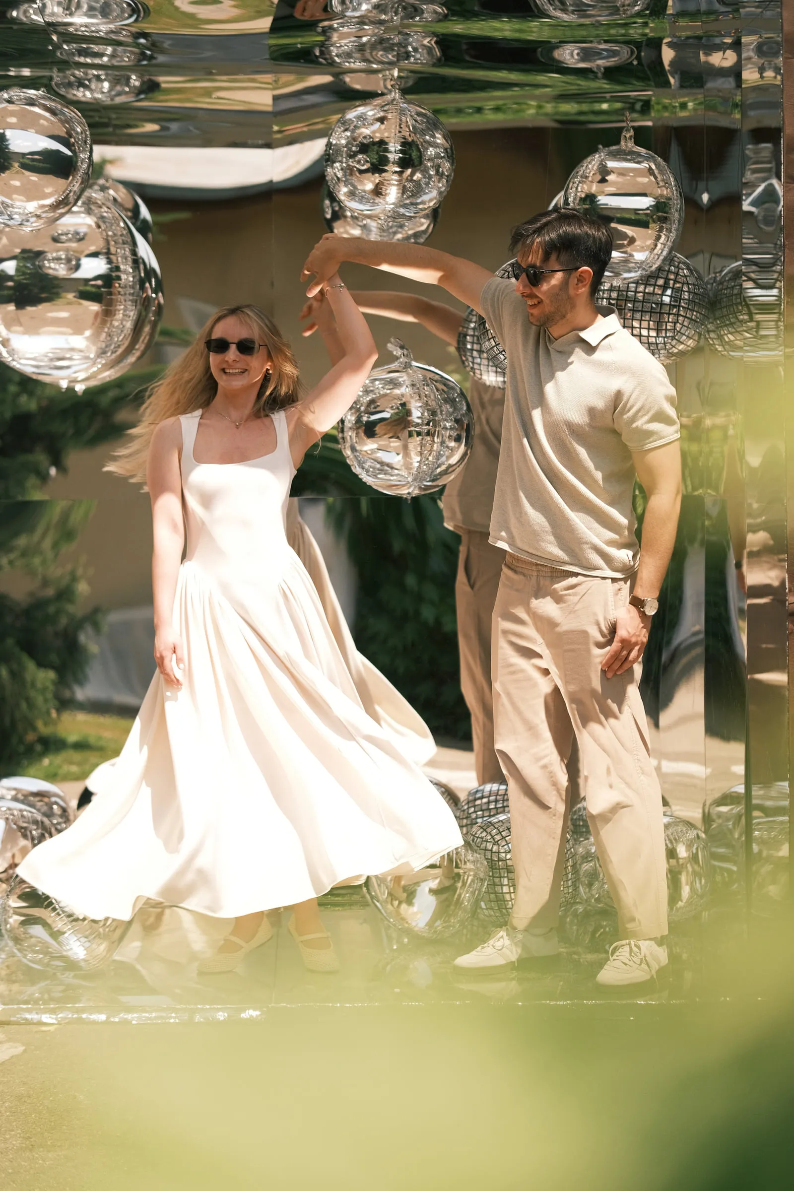 A couple dance among hanging mirrored disco balls, her white dress swinging out