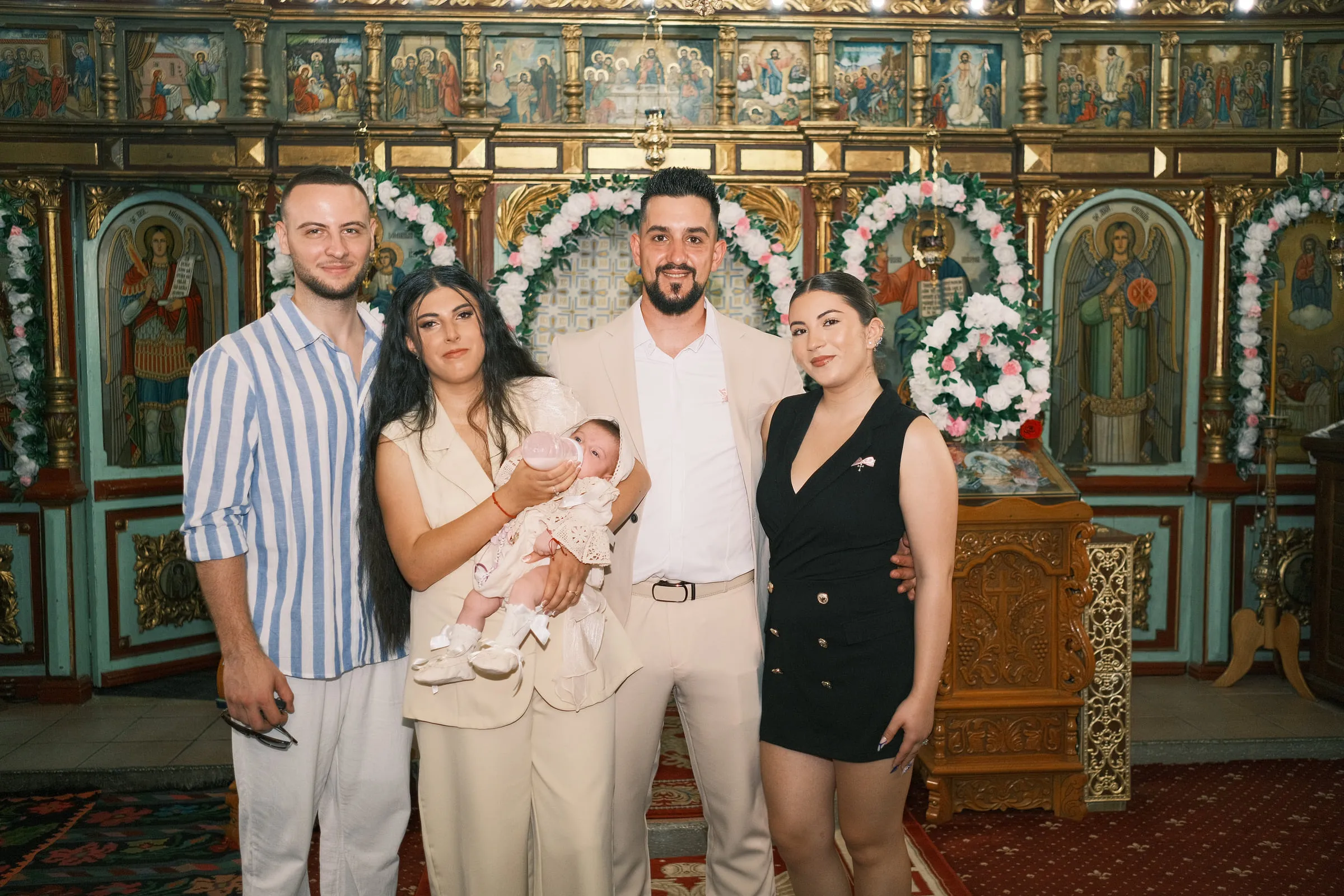 The parents, baby and godparents pose together before the painted iconostasis