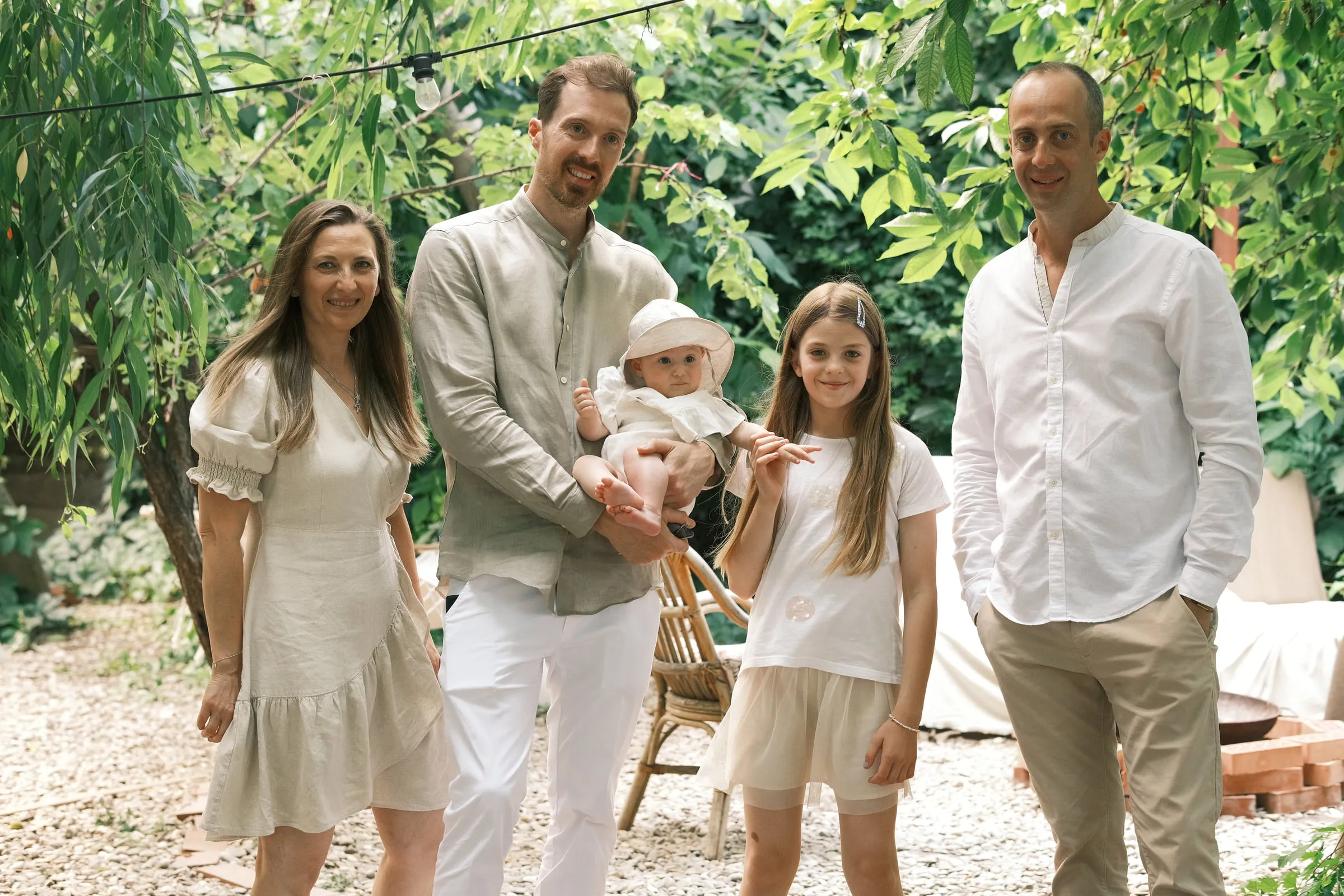 Family portrait in the garden, the father holding the baby in her sun hat