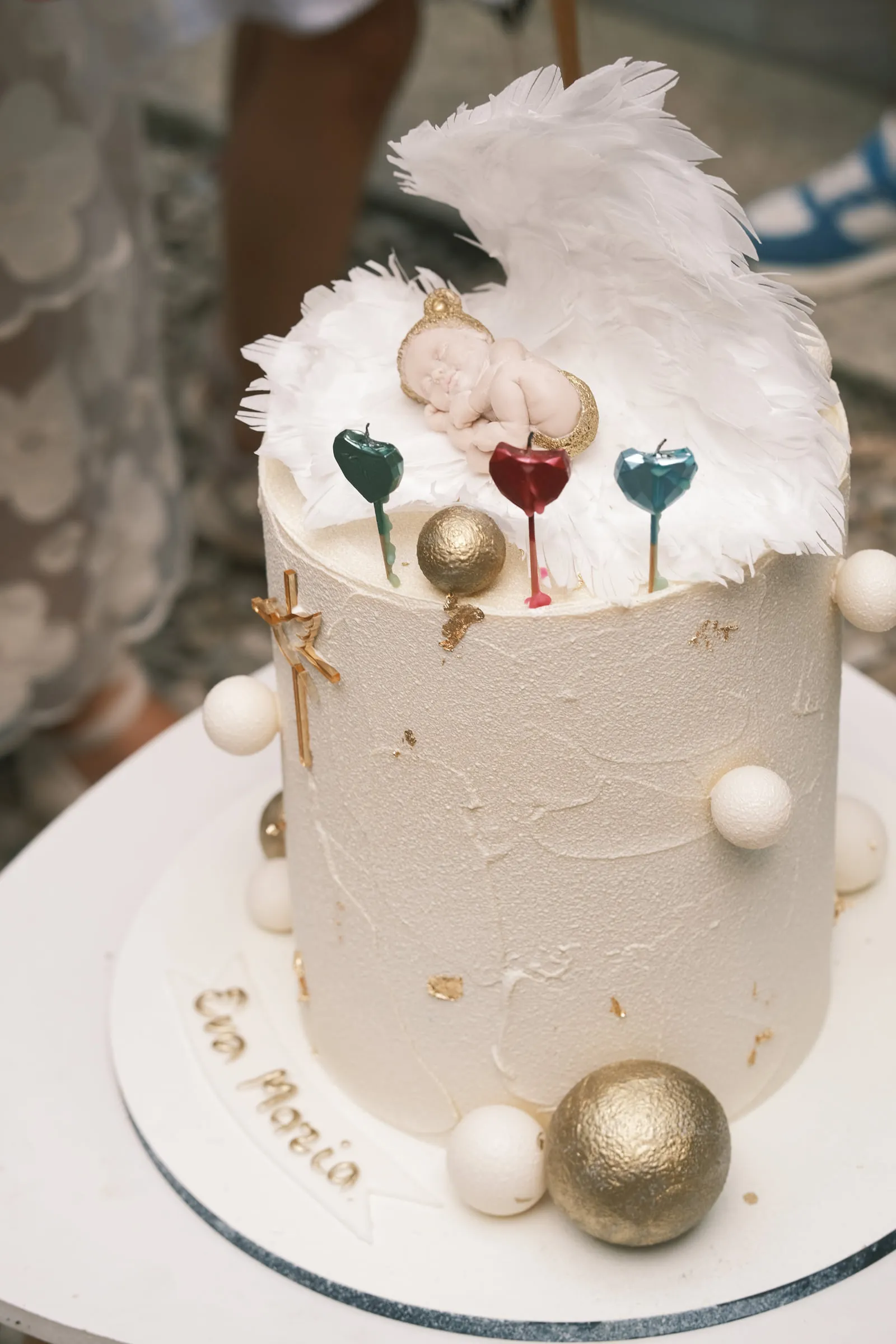 The christening cake, topped with white feathered wings, a sleeping baby figure and the name Eva Maria