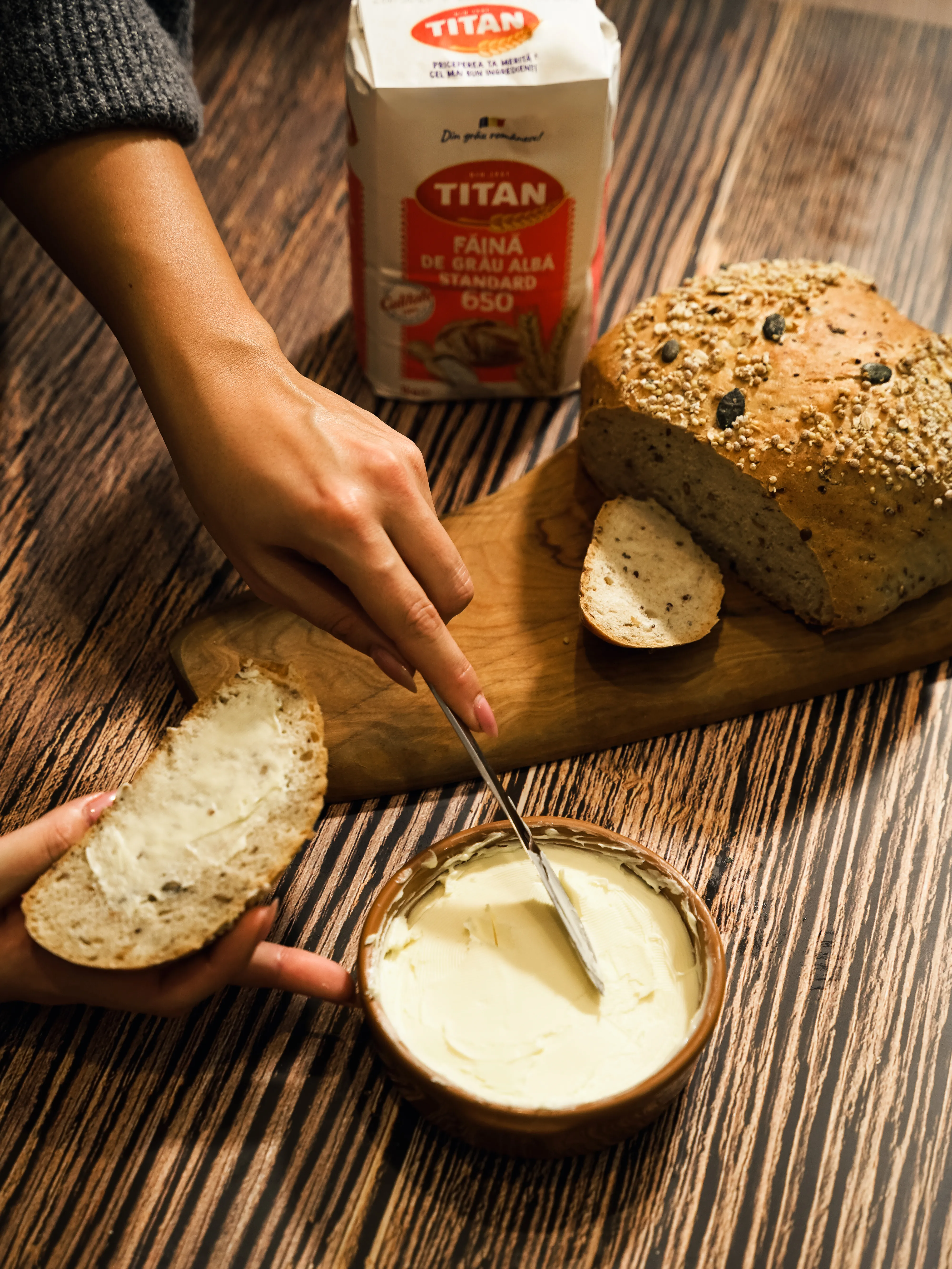 A hand spreading butter on fresh bread
