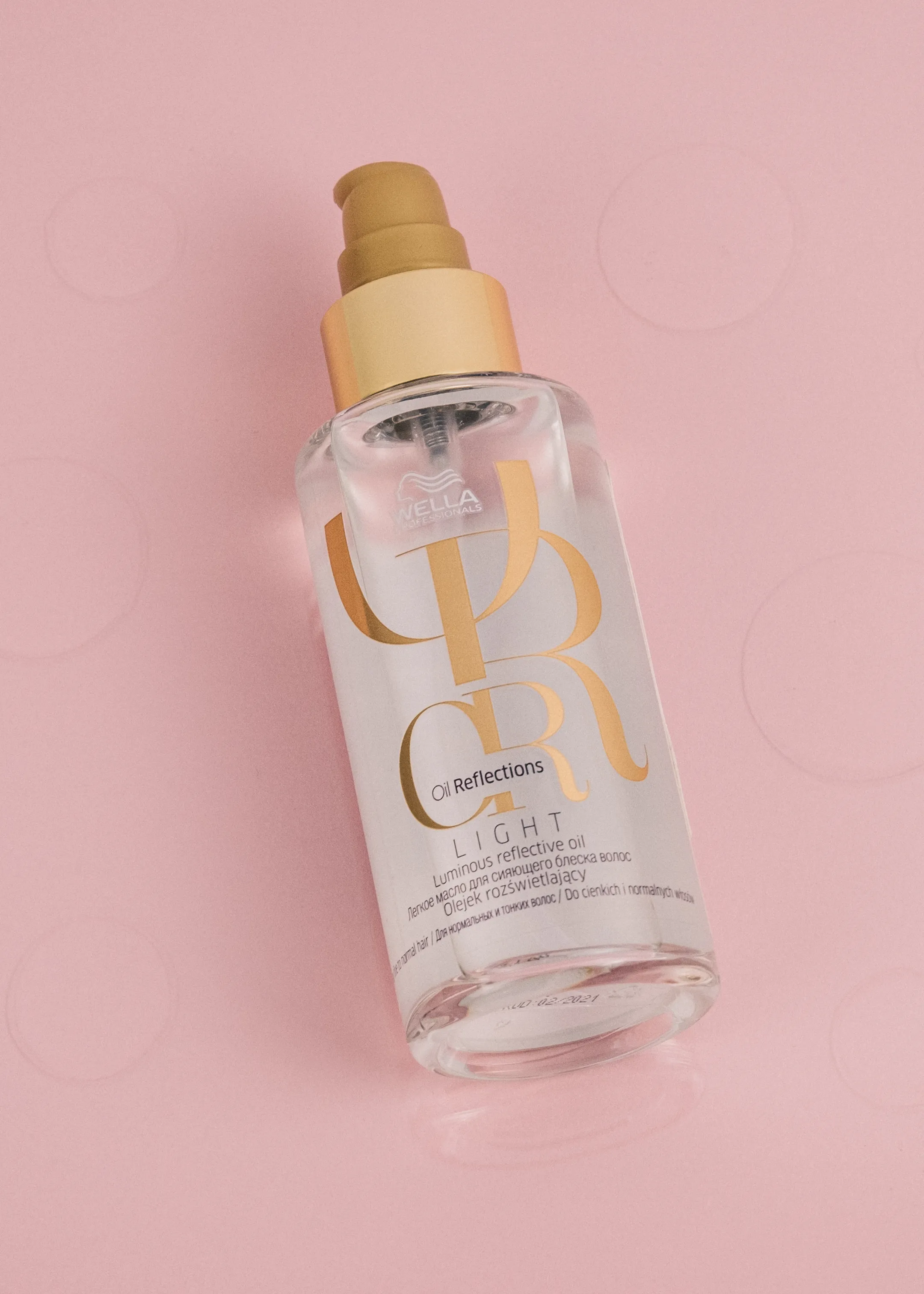 A hair oil bottle on a pink polka-dot background